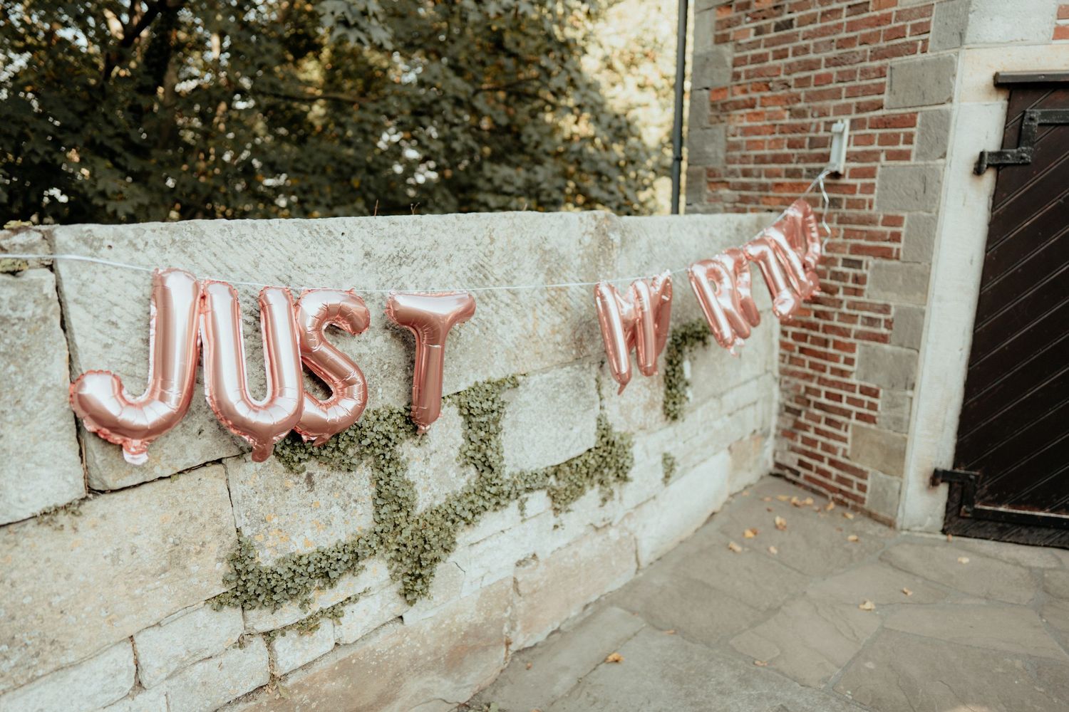 Rosa Ballon-Schriftzug Just married an einer Backsteinwand