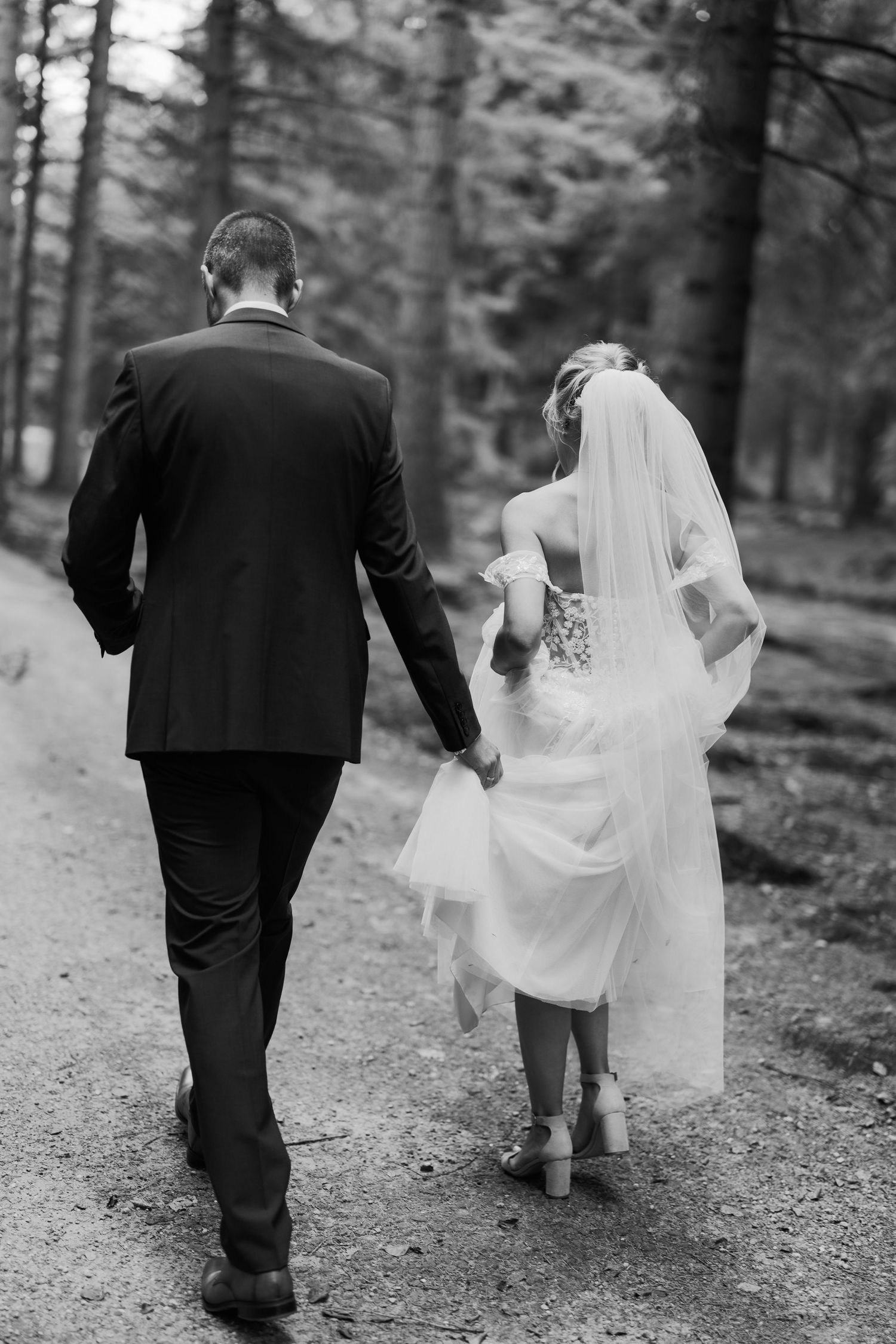 Brautpaar geht Hand in Hand durch den Wald, Schwarzweiß