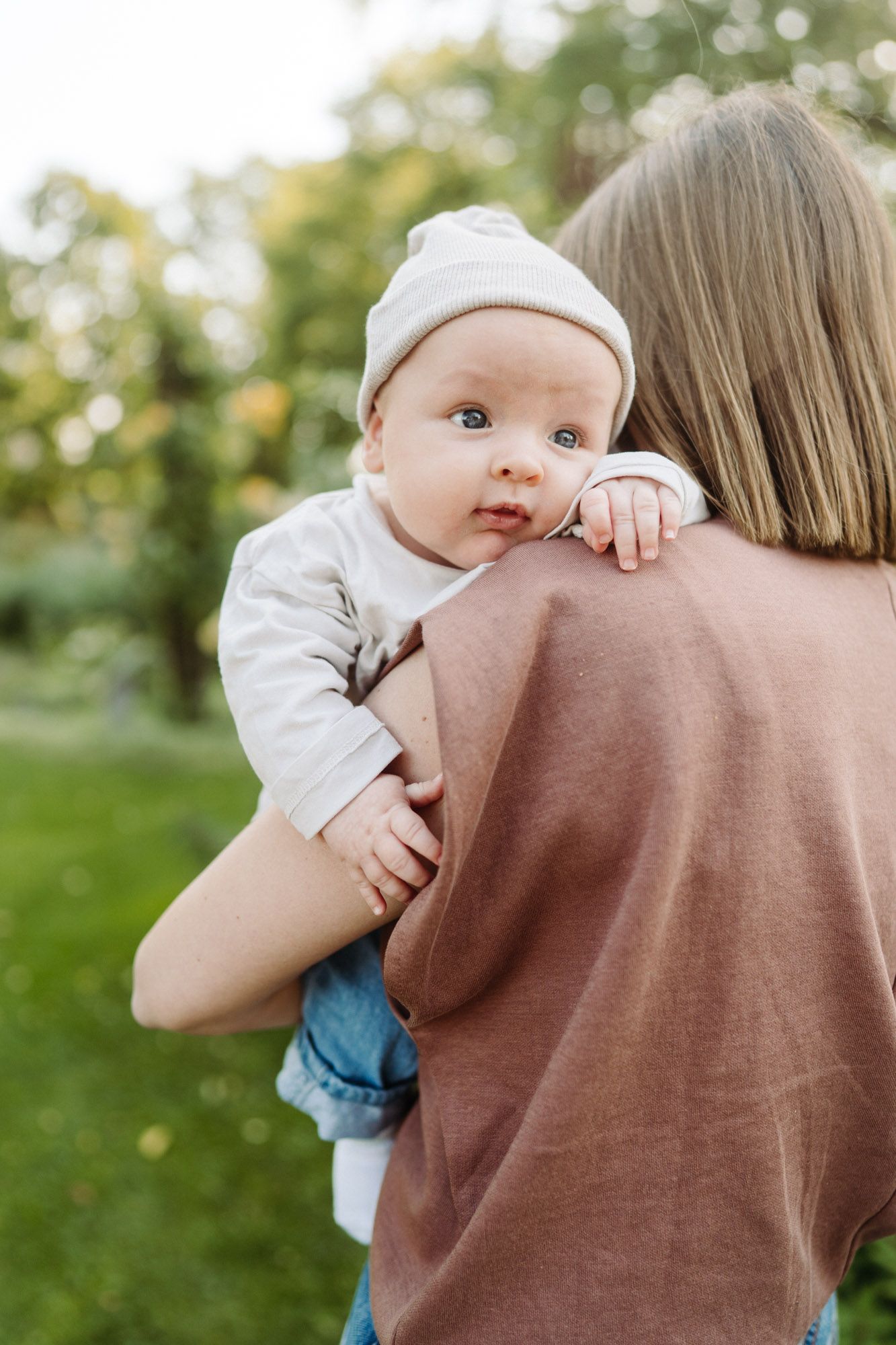 Mutter trägt ihr Baby mit Mütze auf dem Arm