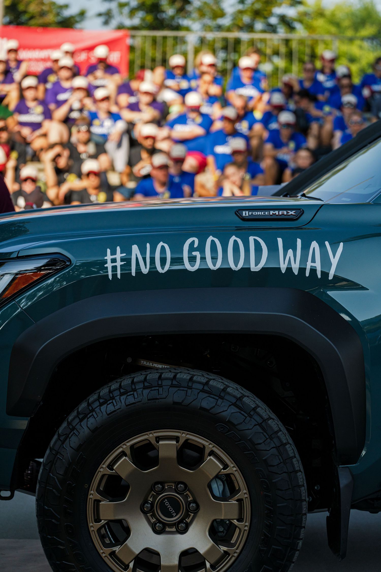 Black SUV with custom wheels and '#NOGOODWAY' text decal visible in a crowded outdoor setting.