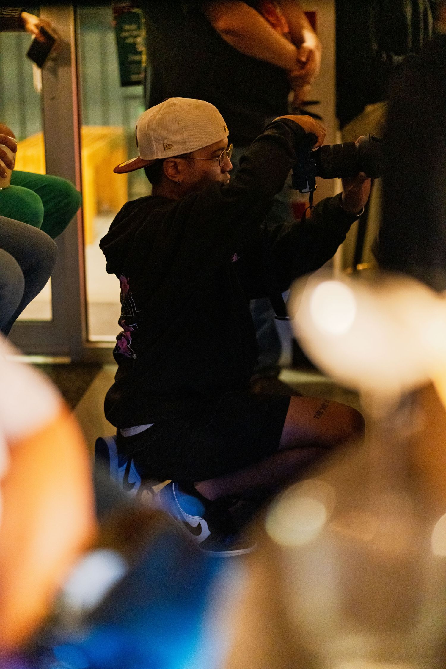 Blurred silhouettes of audience members watching a performance in a dark venue.