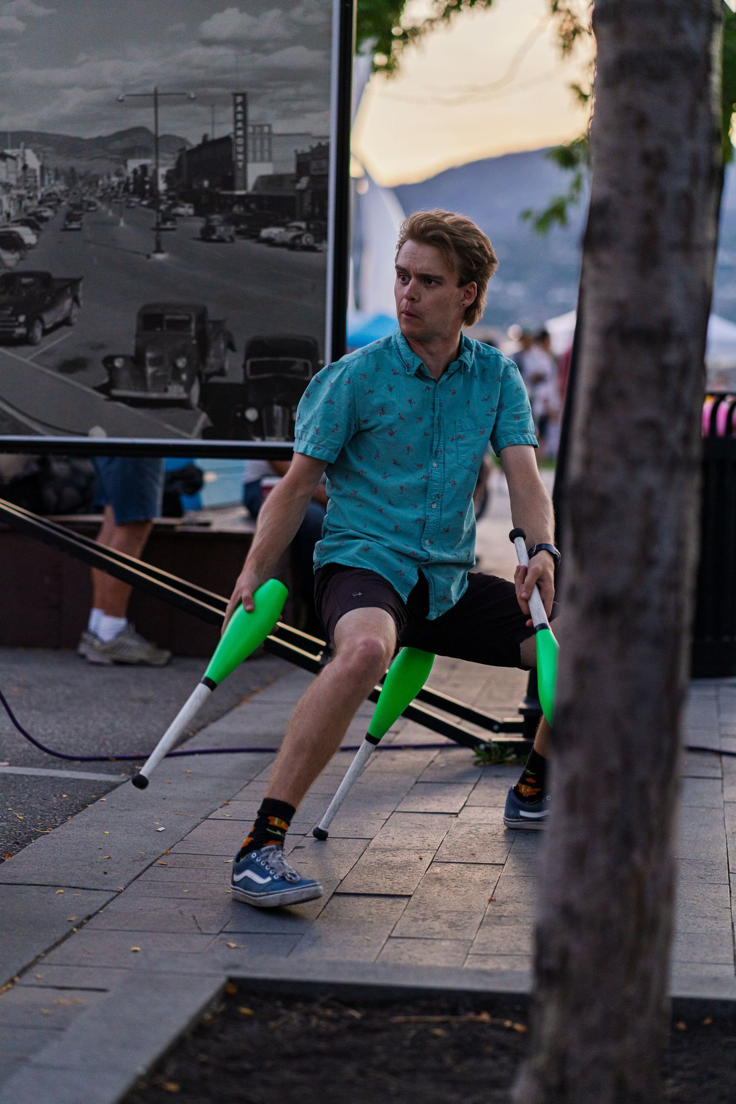A person in a turquoise shirt performs stretching exercises on an urban sidewalk.