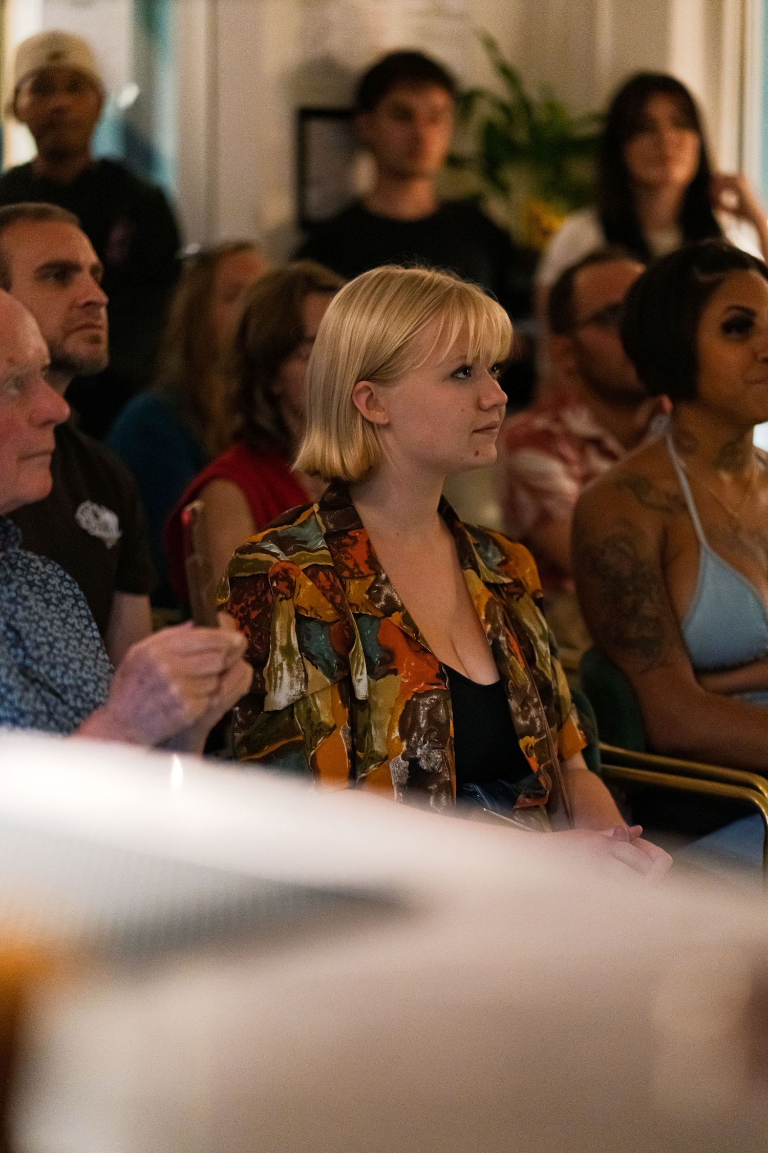 Audience members watch intently during an indoor event or presentation.