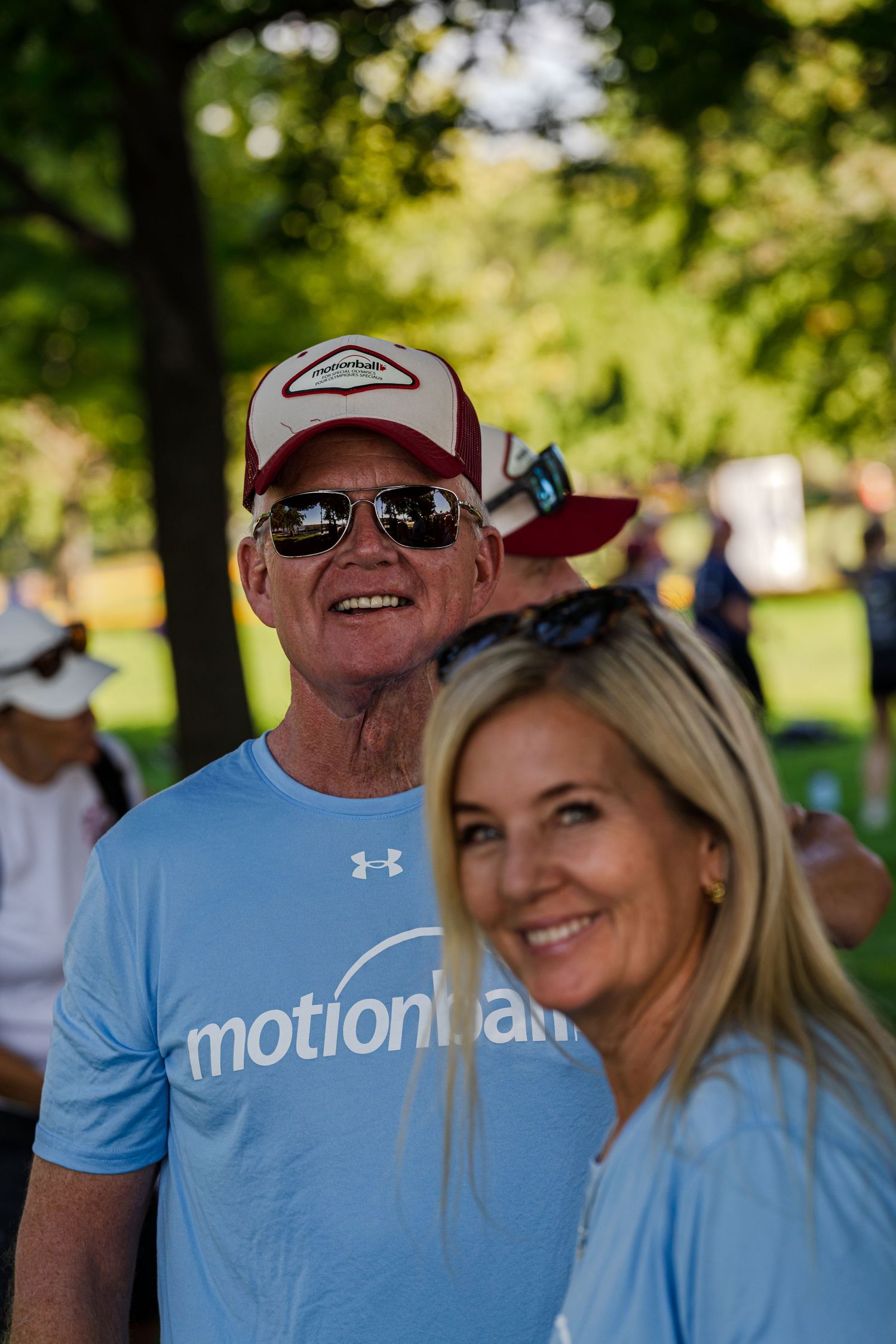 People enjoying a sunny outdoor event wearing casual athletic clothing and baseball caps.