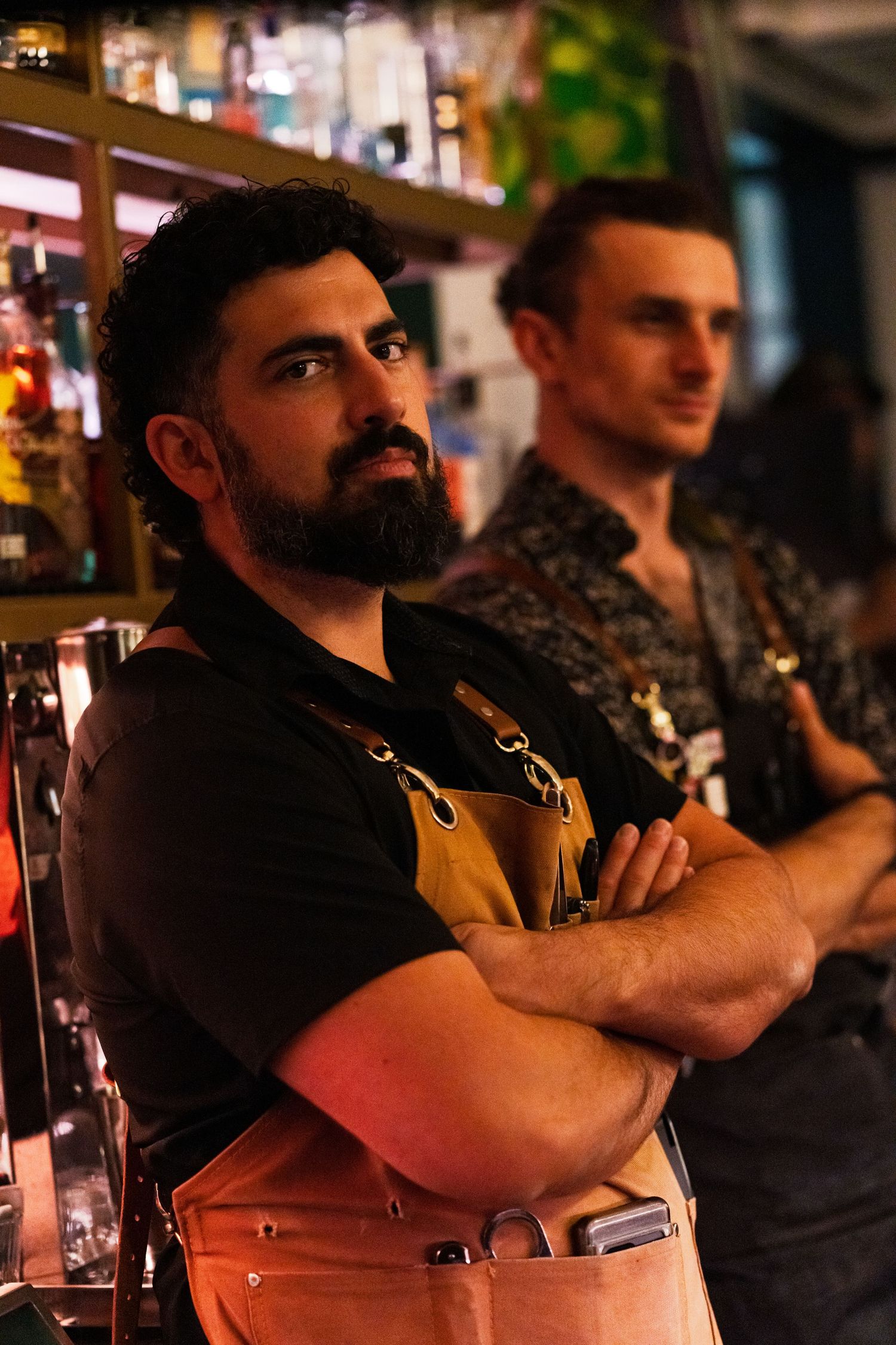 Group of people sitting at a bar counter in warm ambient lighting.