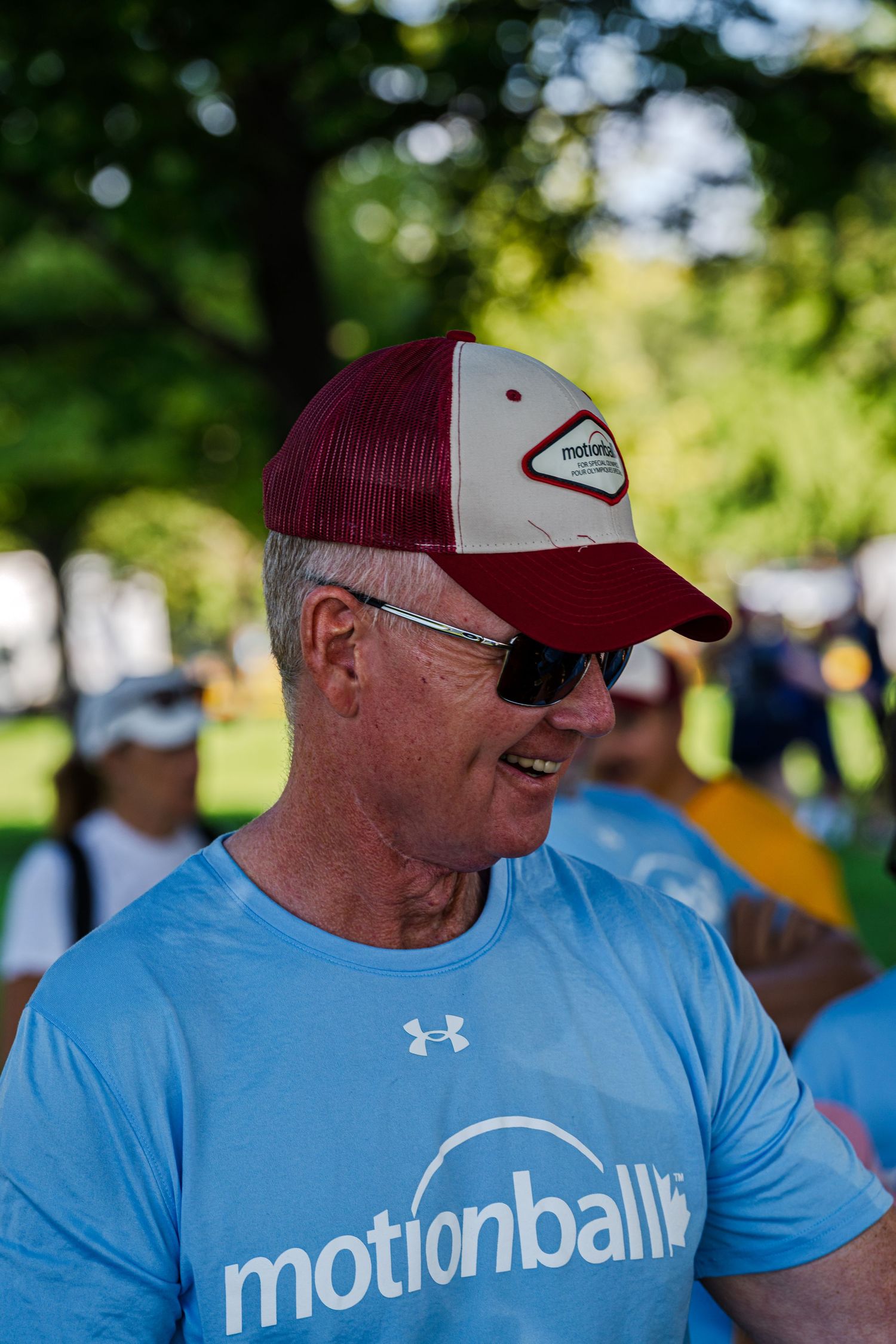 A person wearing a blue t-shirt and red baseball cap at an outdoor event.