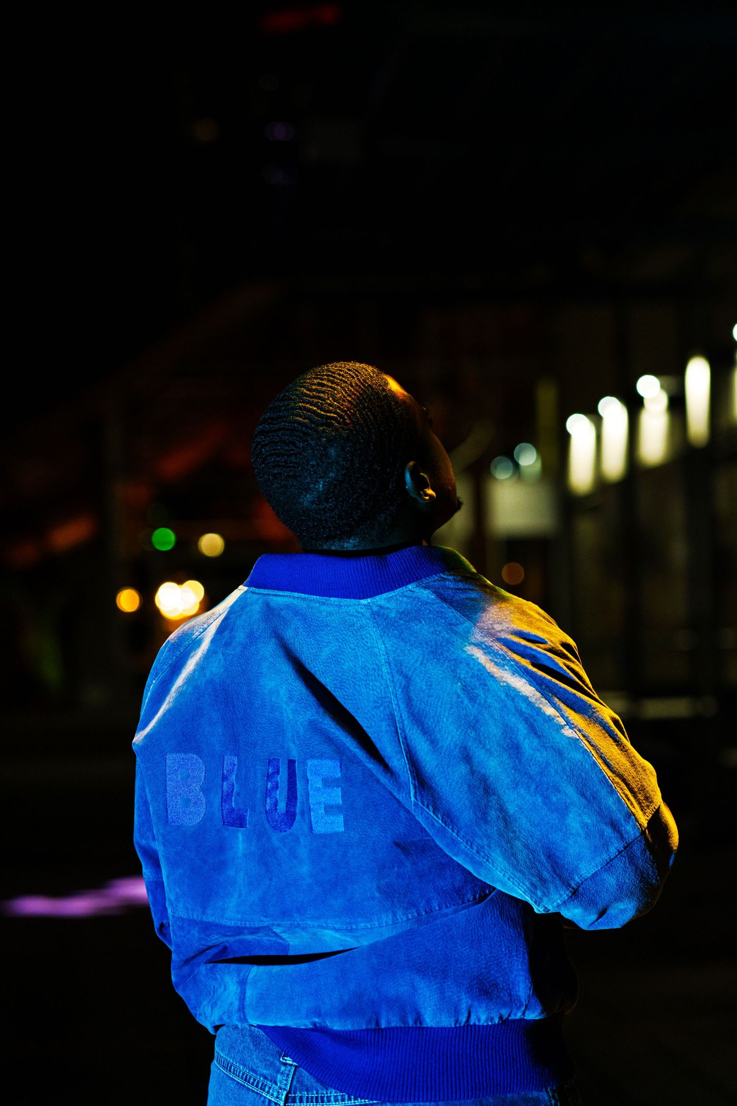 Person wearing bright blue jacket shown in sequence of nighttime photos with blurred lights in background.