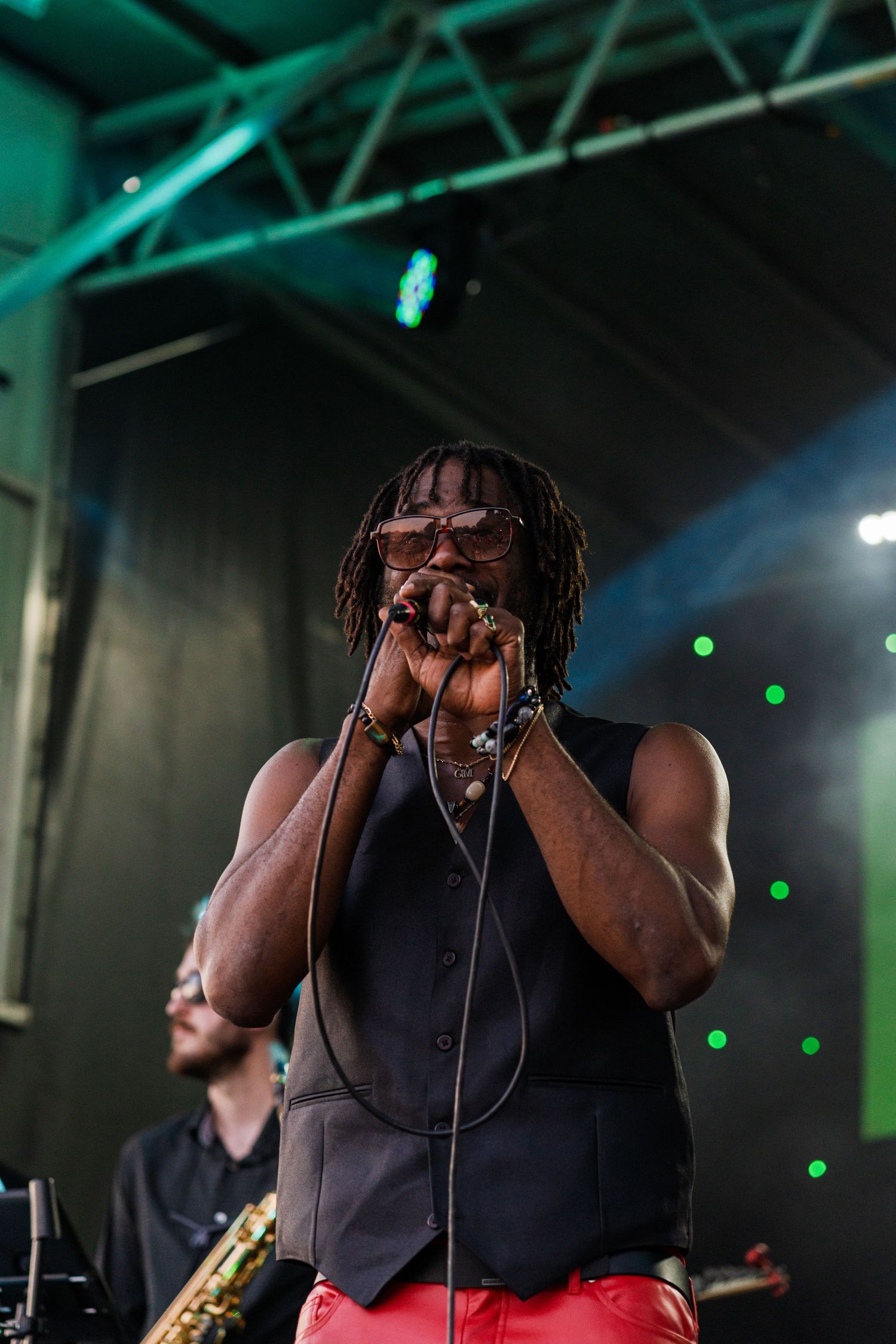 Performer singing passionately on stage with dramatic lighting and microphone.