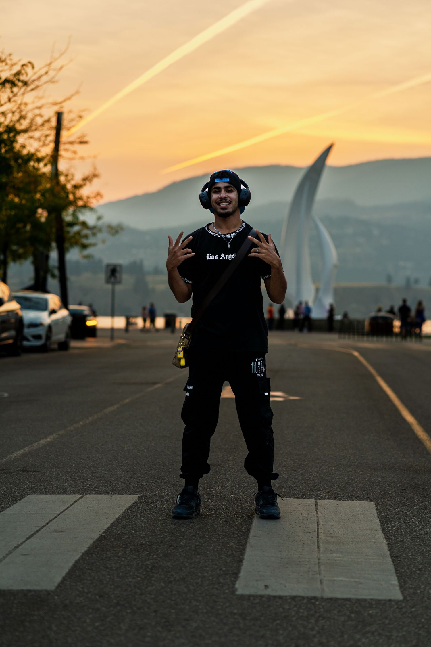 Person in black clothing performs dance moves at sunset against a mountain backdrop.