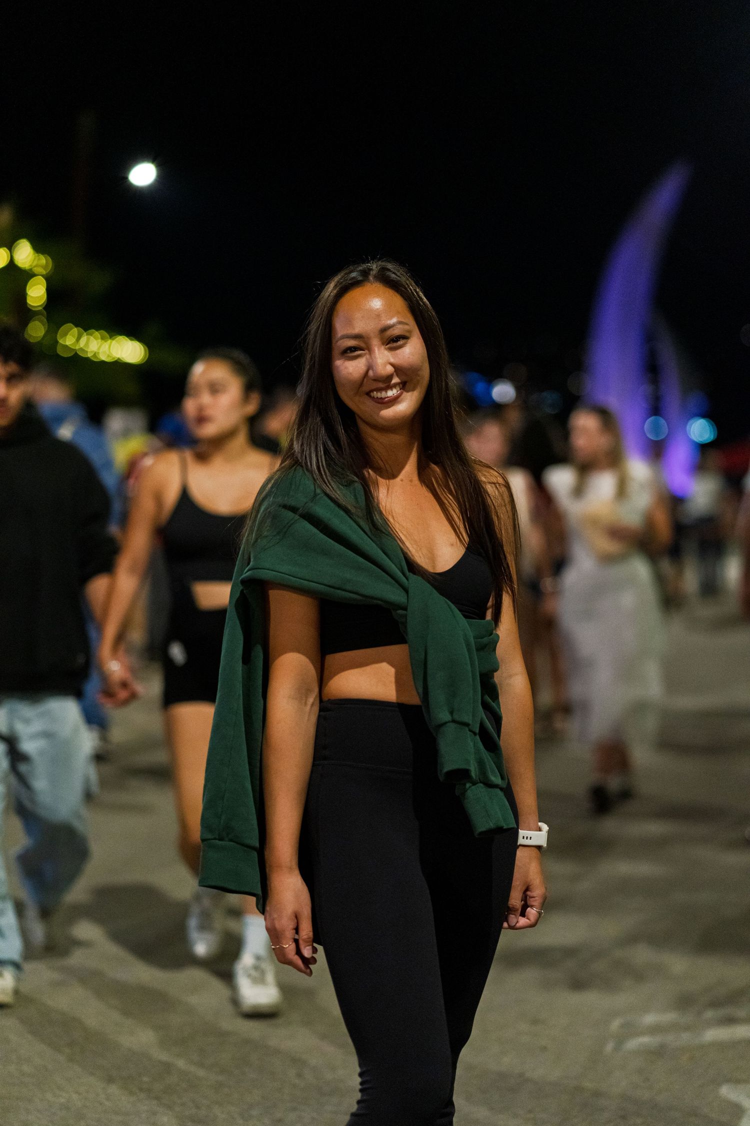 People walking at night with colorful lights and a dark urban atmosphere.