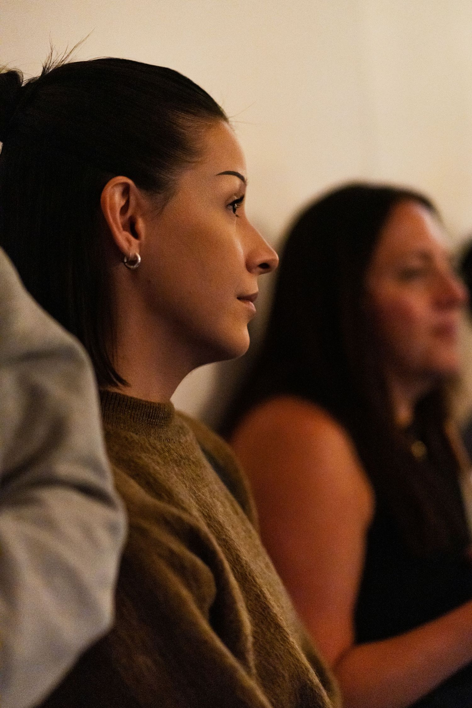 Profile view of people watching intently in a dimly lit setting.