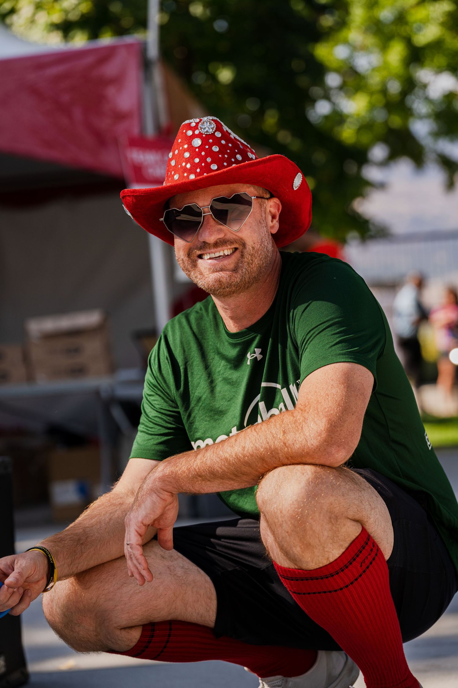 Person in green shirt and red hat relaxing at an outdoor summer event.