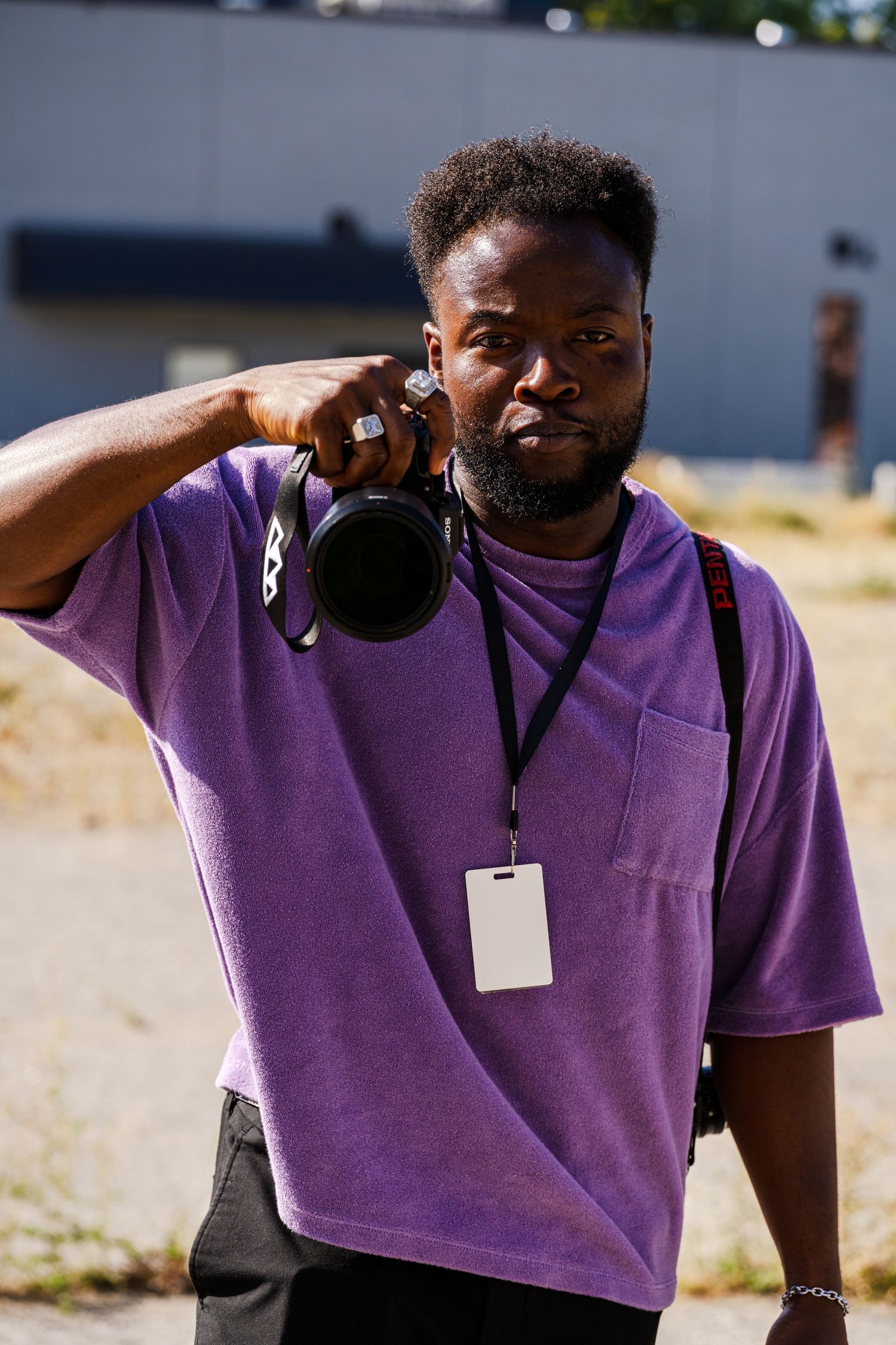 Person wearing purple t-shirt and lanyard in outdoor setting.