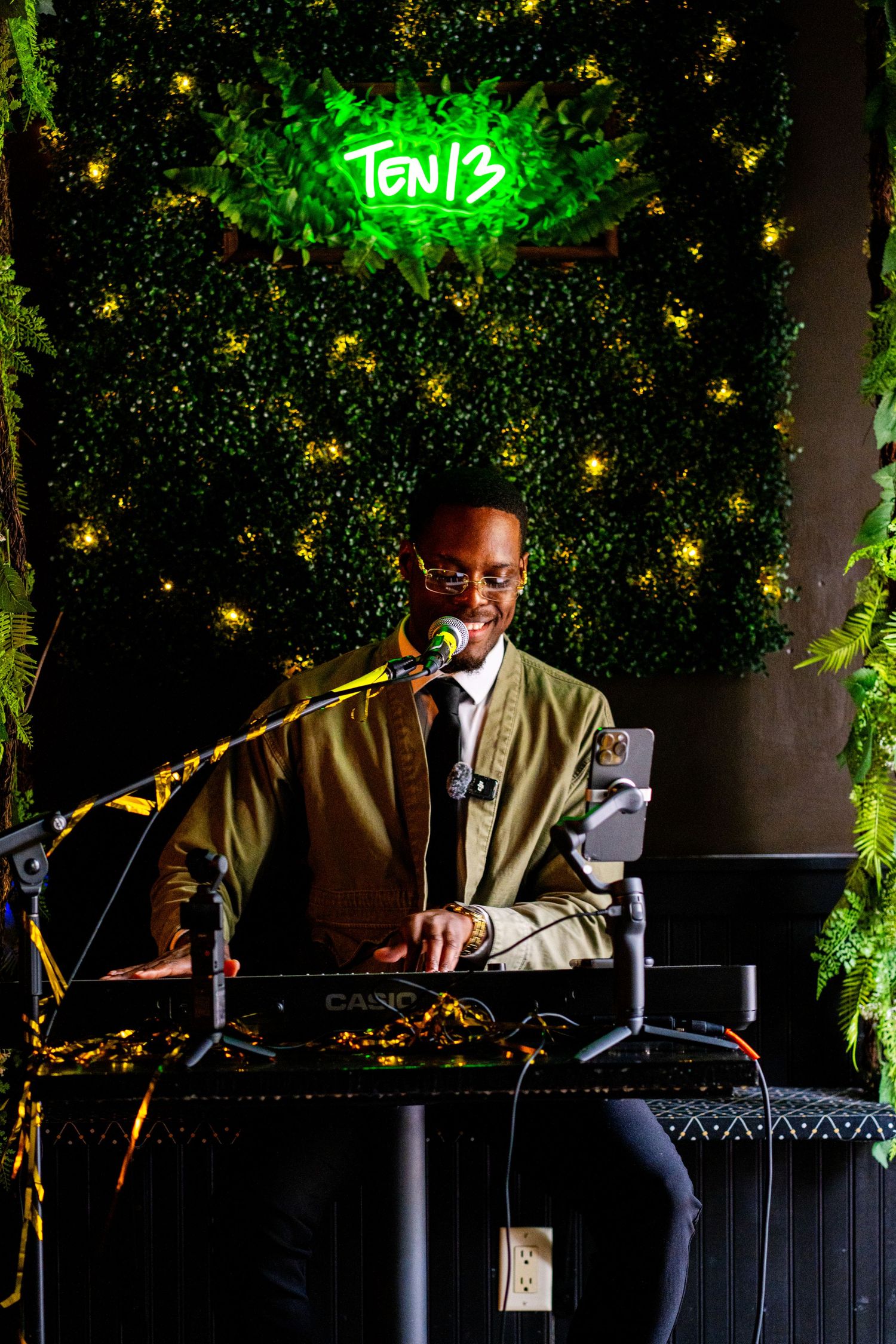 DJ performs at a nightclub setup decorated with green lighting and twinkling lights.