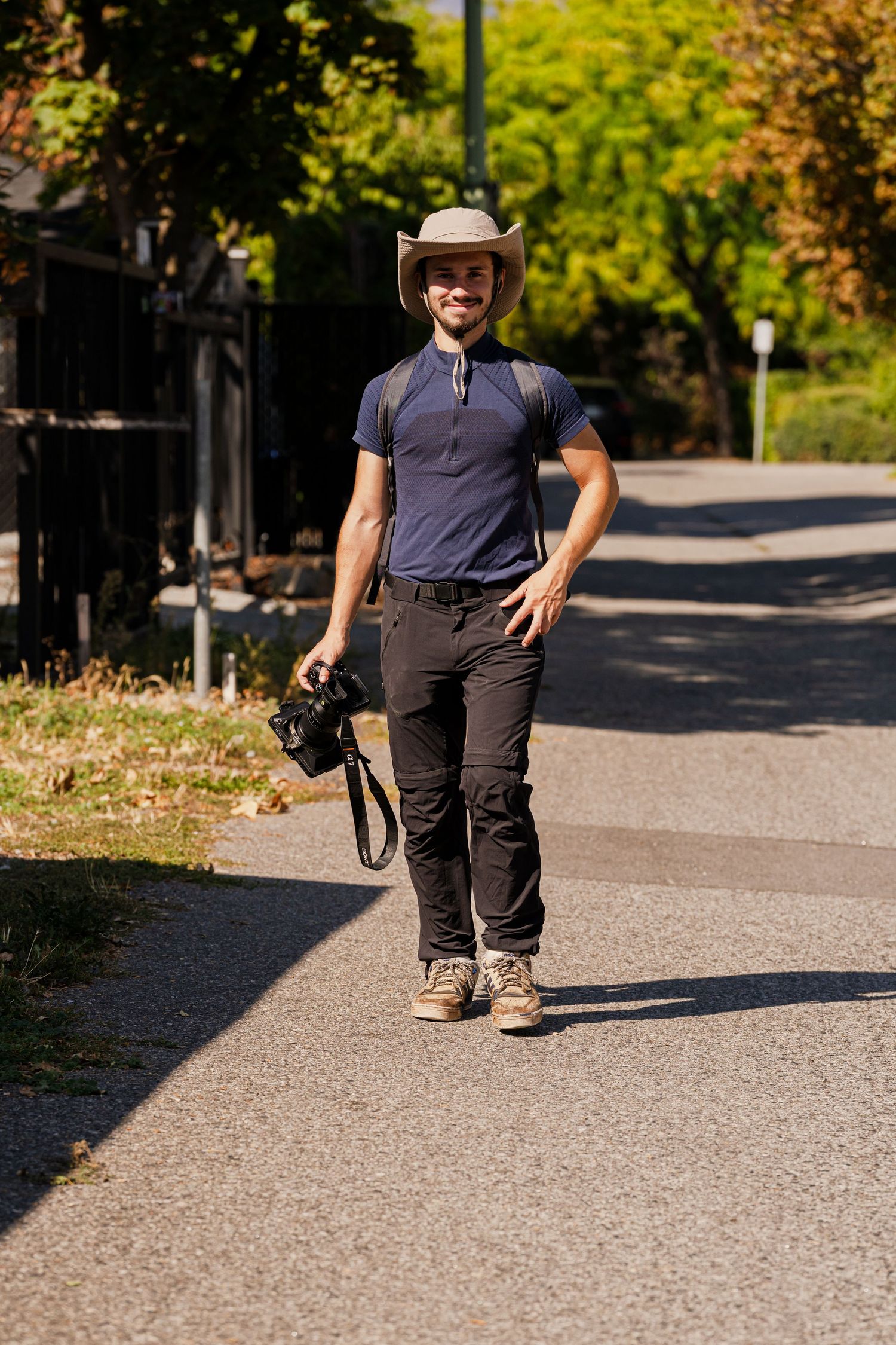 Person crouches on a paved pathway surrounded by greenery in an outdoor setting.