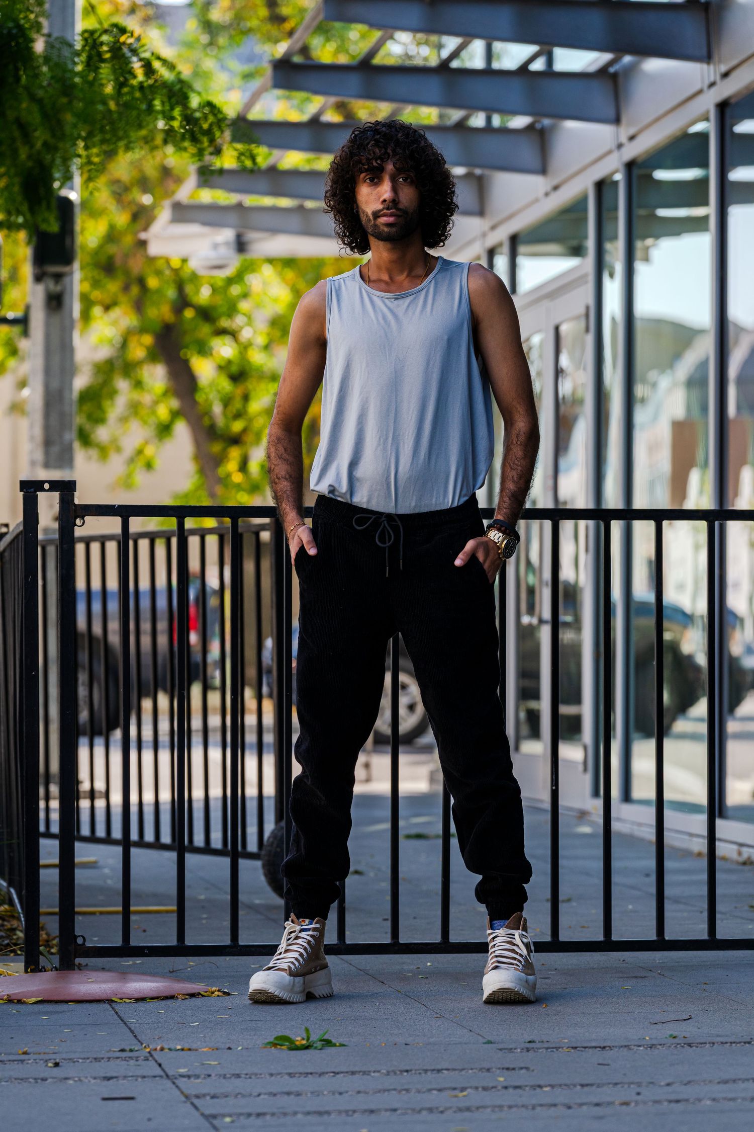 Person in athletic wear demonstrating dance moves near a metal railing outdoors.