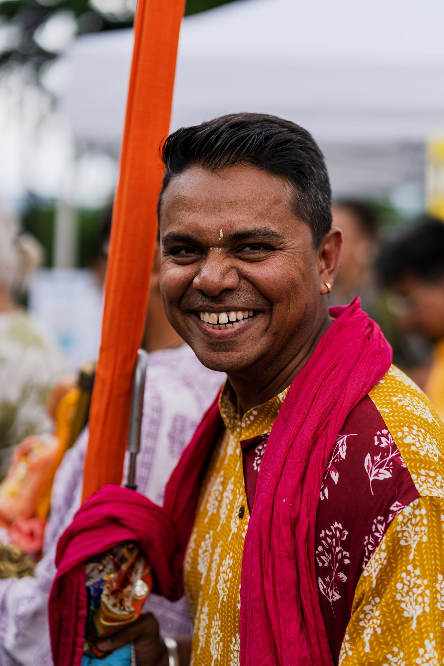 Person wearing vibrant yellow and pink traditional attire smiles during a cultural celebration.