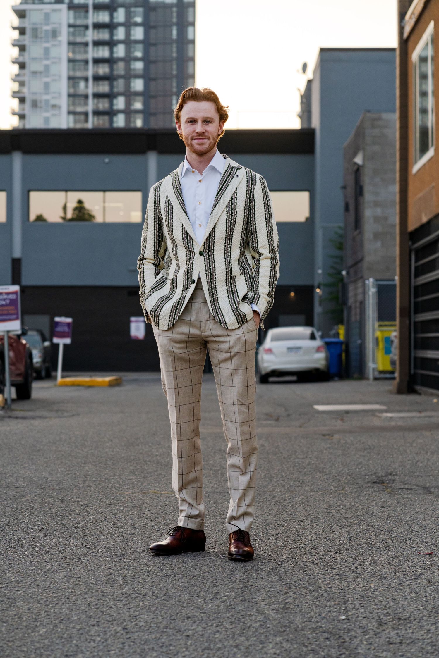 Person in stylish striped suit standing in urban setting with high-rise buildings in background.