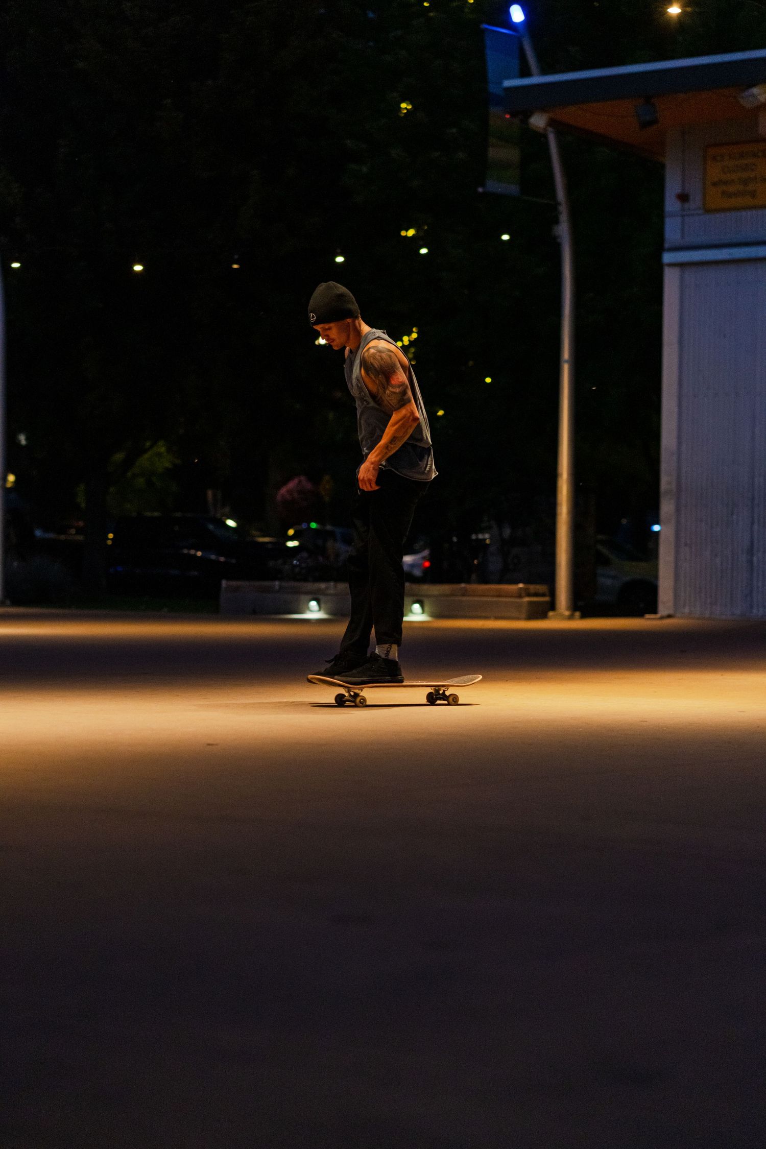 Skateboarder performs tricks in a dimly lit outdoor space at night.
