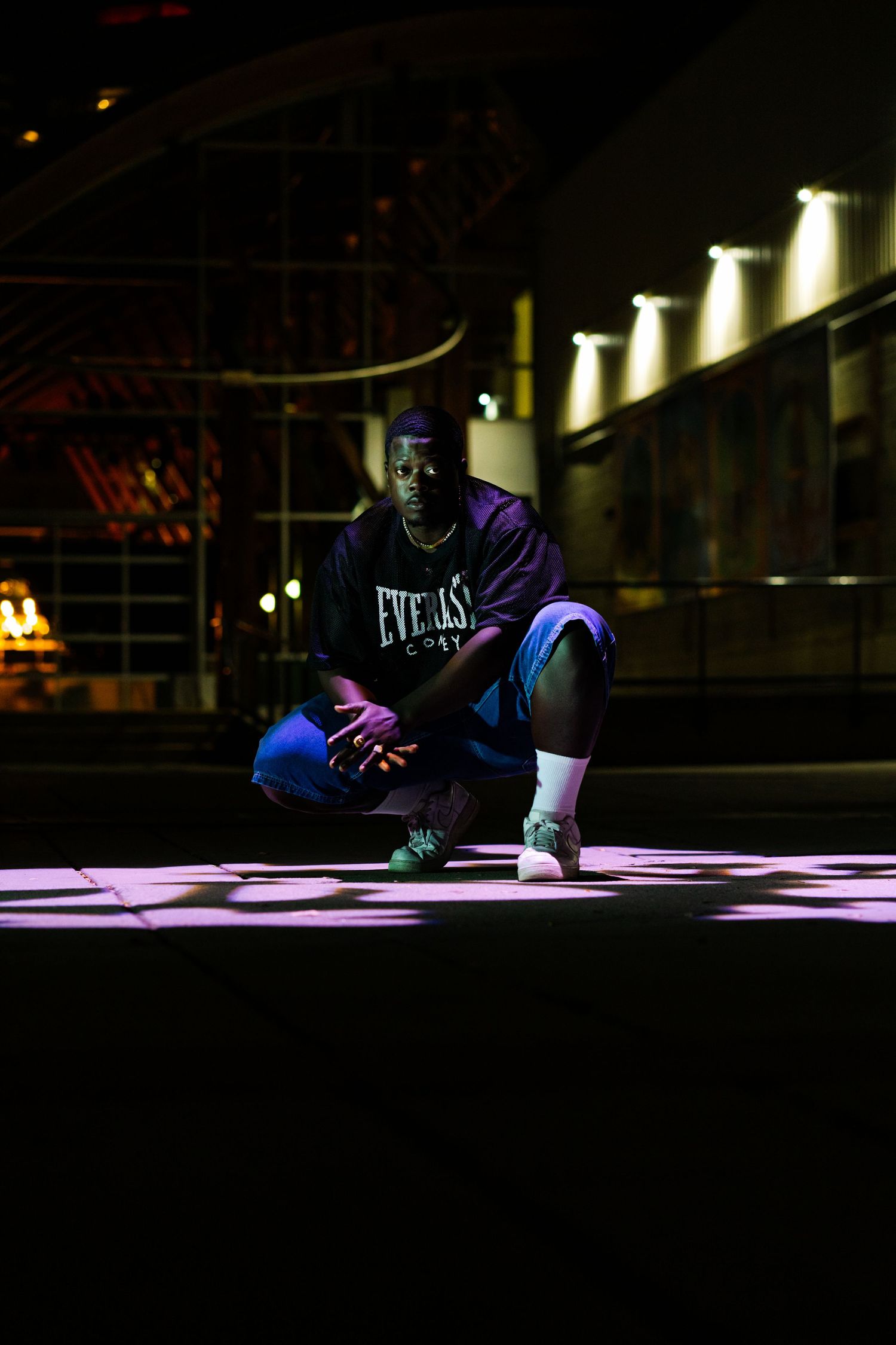 Person performing breakdancing moves on illuminated purple floor in dark environment.