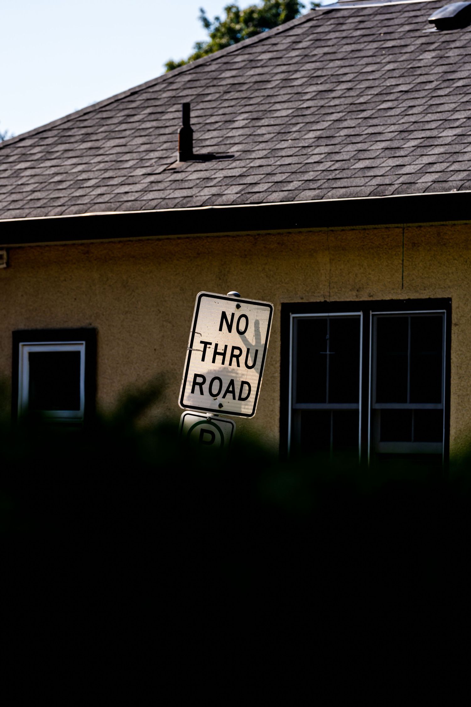 A series of rooftop signs on a building including 'No Thru Road' and other traffic signage against a dark background.