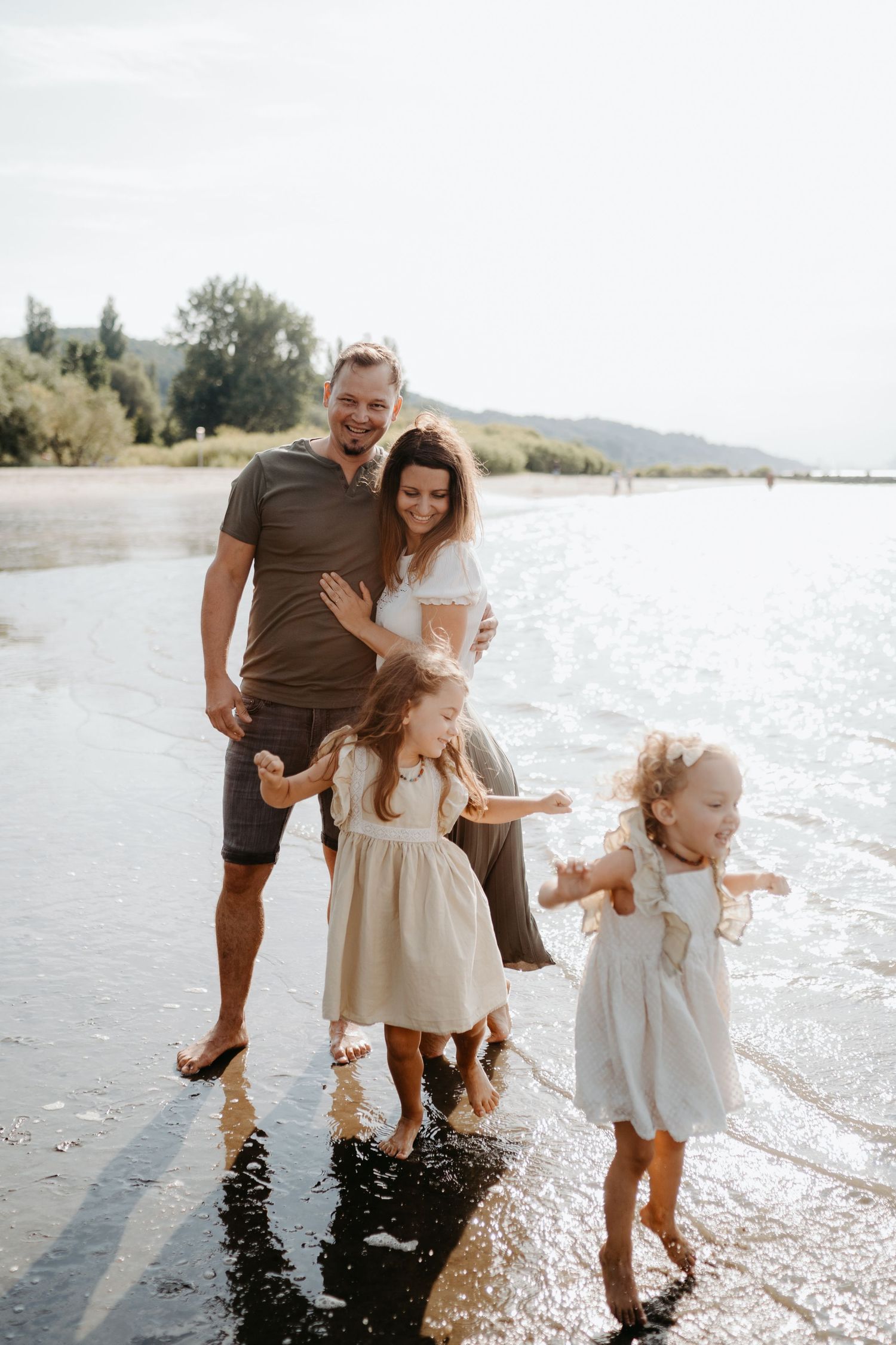 Family enjoying a sunny day at the beach together playing in the shallow water at sunset.