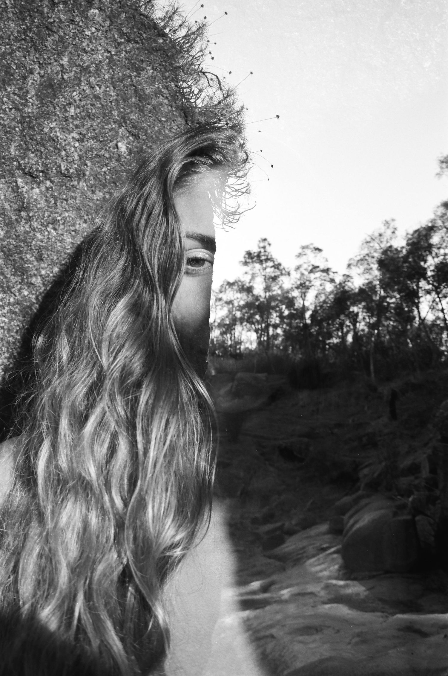 Grounded feminine portrait among cracked river stones — slow, intentional film shoot in the Perth Hills at sunrise.