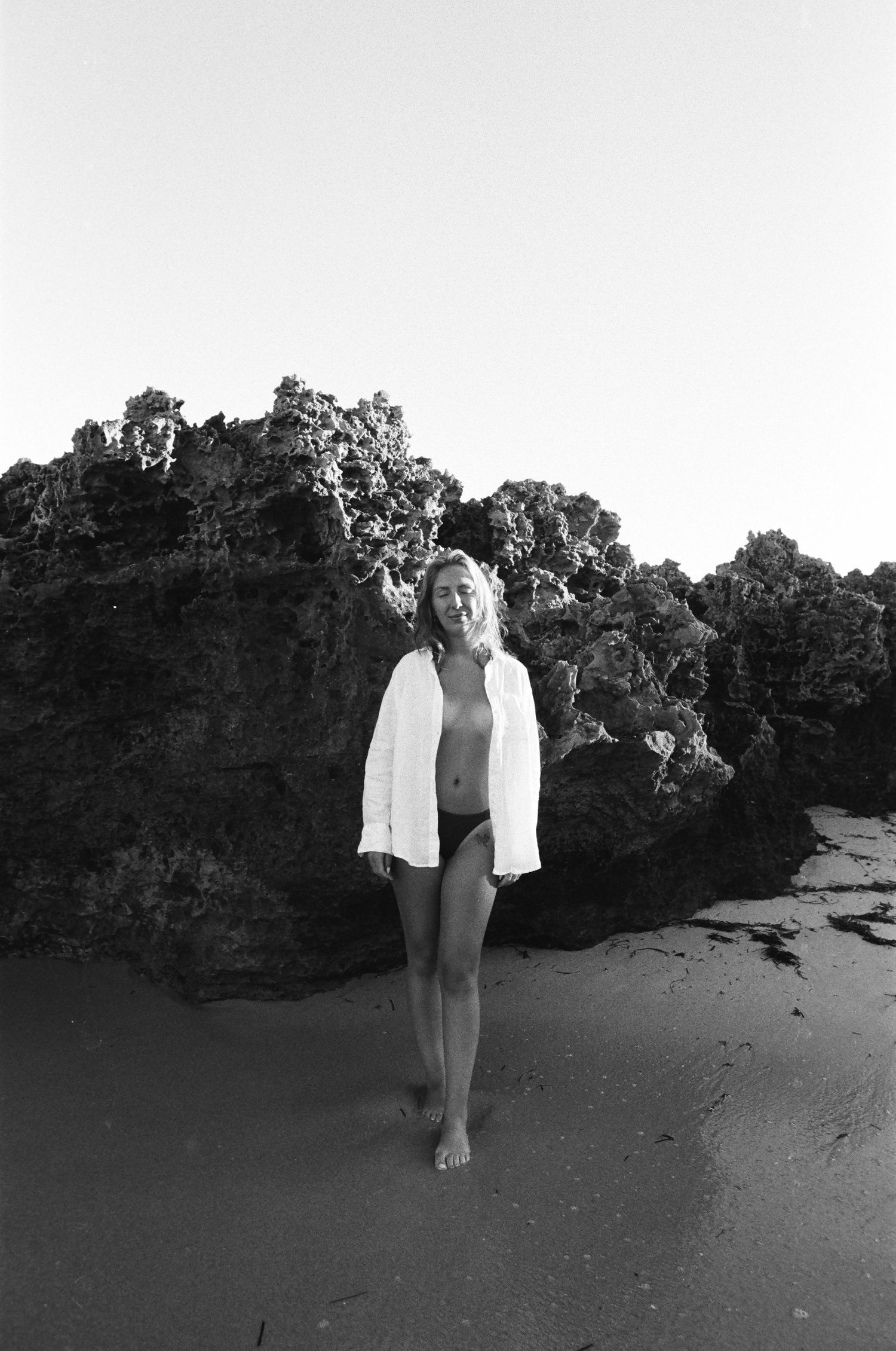 Woman standing in gentle ocean tide during golden hour — film photography at Trigg Beach, Perth.