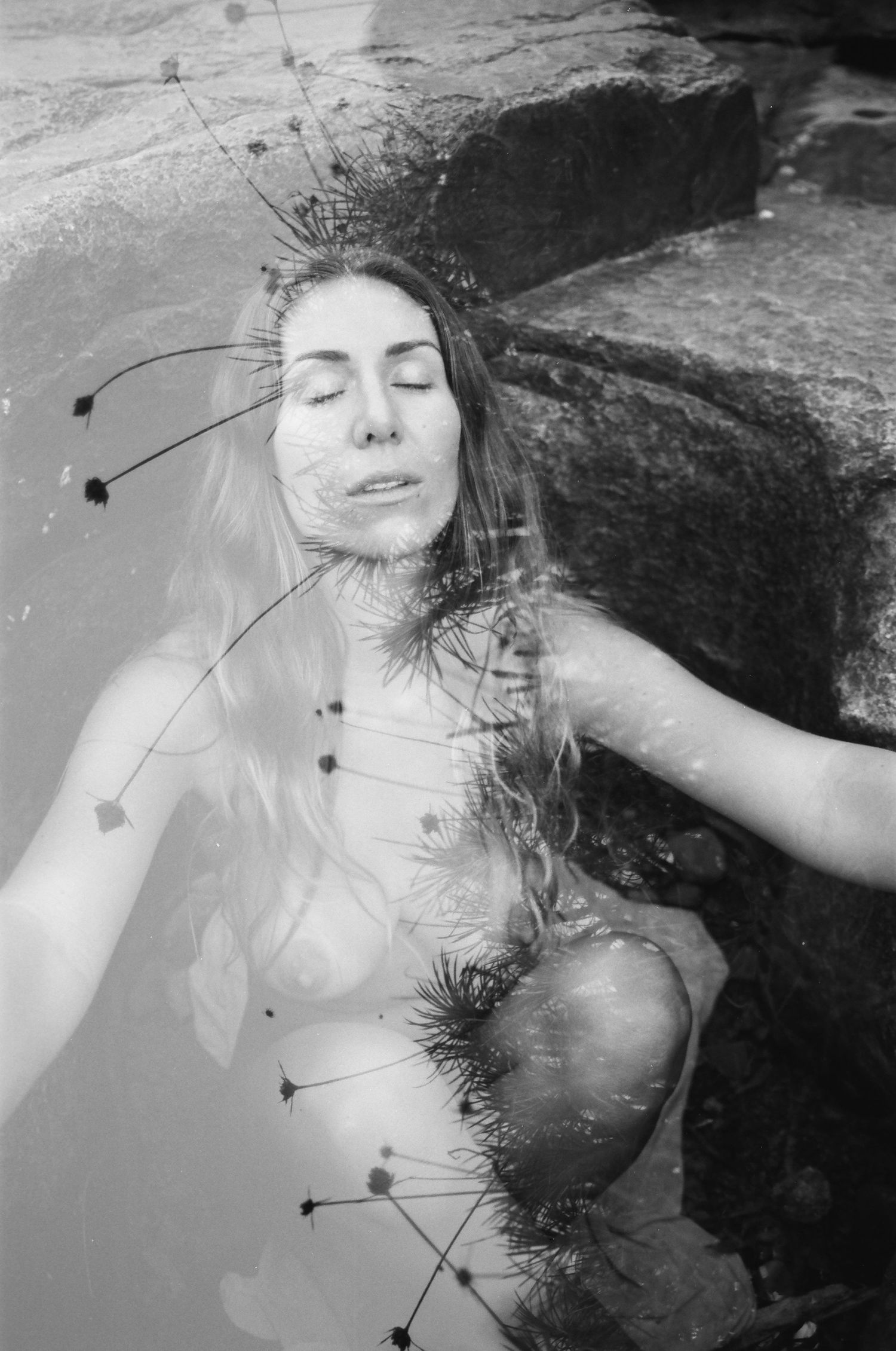 Woman moving slowly across sunlit rocks at dawn — embodiment film photography in the dry riverbeds of the Perth Hills.