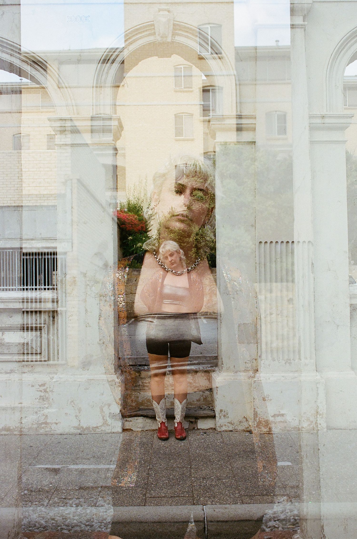 Angie Colman framed by an arched window in West End streetscape.