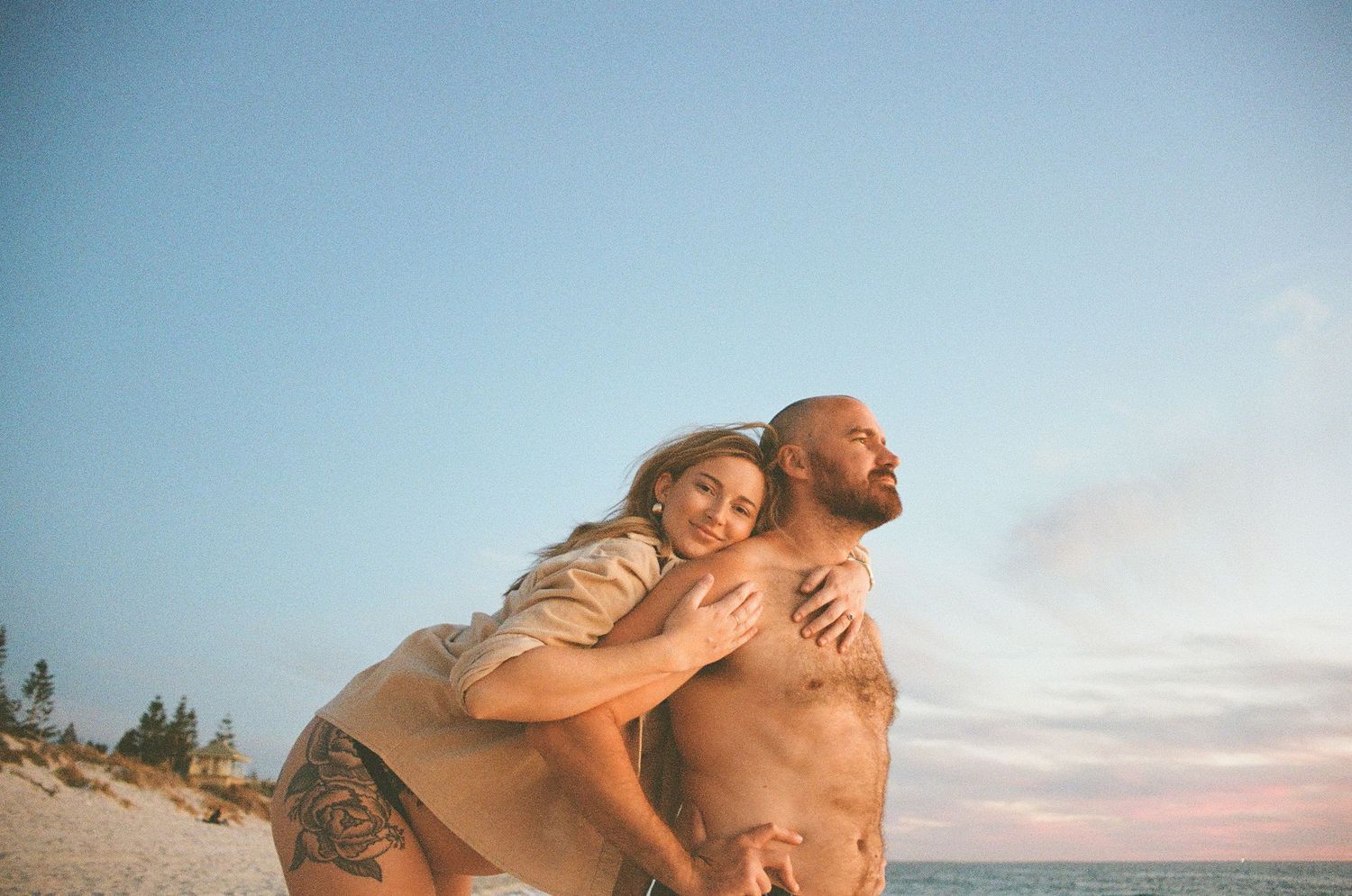 Tender moment of couple by the ocean, captured in natural light maternity photography in Perth.
