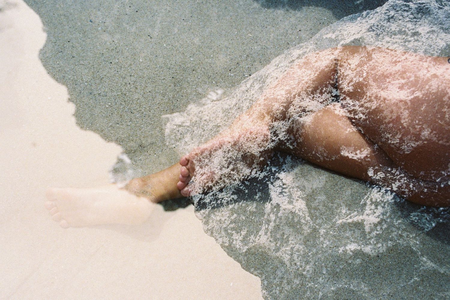 Overhead of feet in a rock pool at Mettam’s, refracted light on film