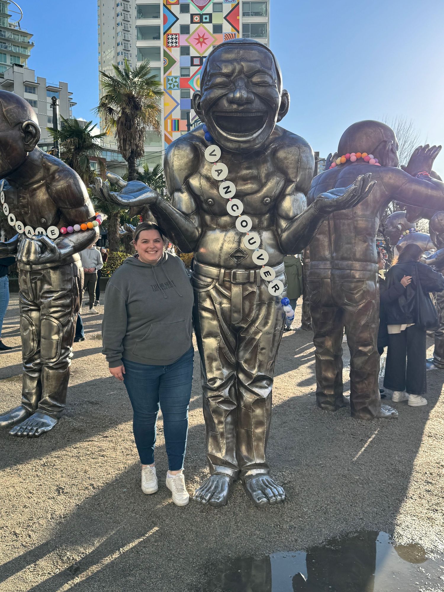 Woman wearing a Taylor Swift hoodie standing next to a statue wearing a friendship bracelet.
