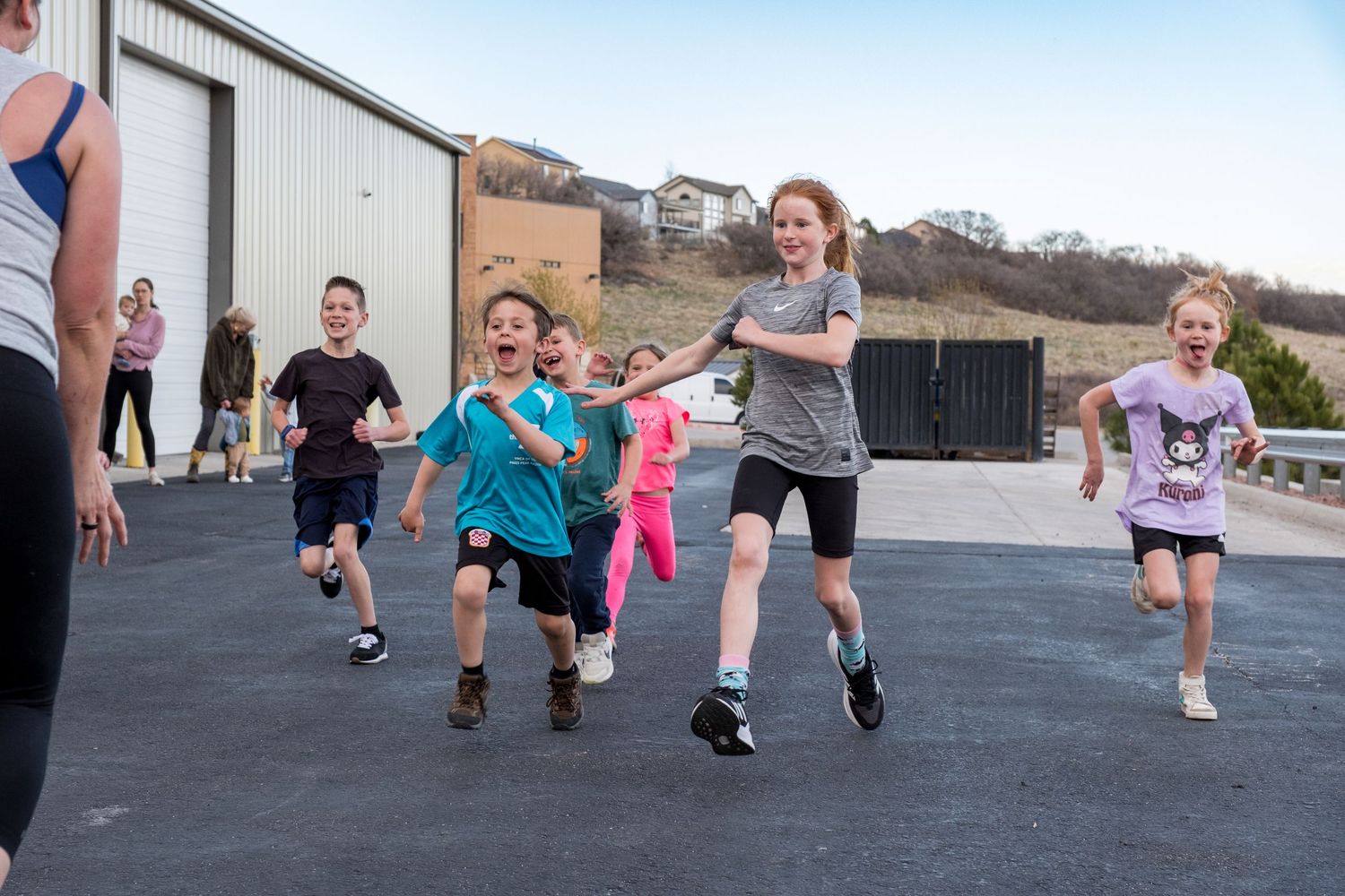 Group of energetic children running outdoors during a CrossFit kids fitness class.