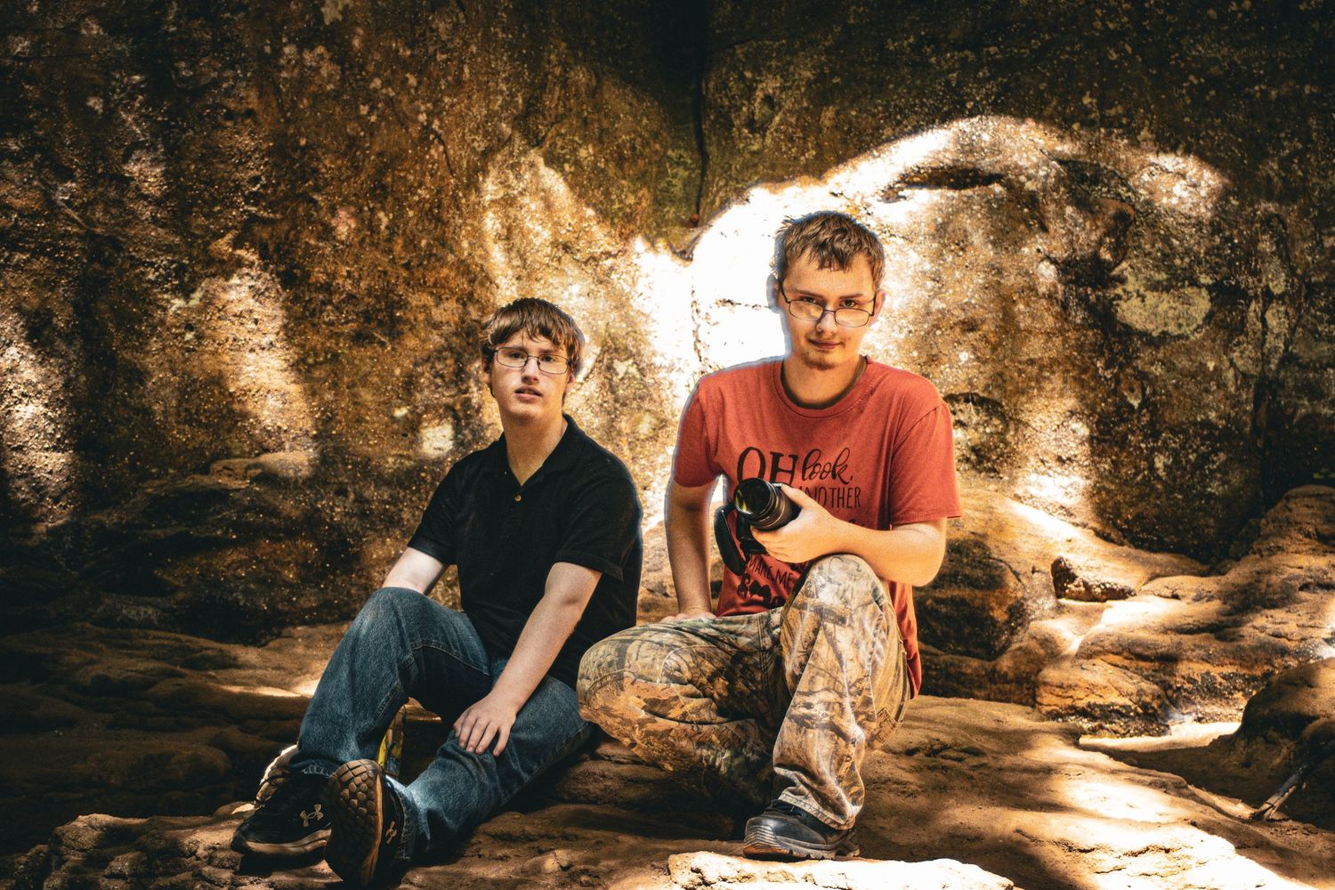 Moody, atmospheric portrait of two young men sitting on rocks, captured by Senbon Studio in Hawesville