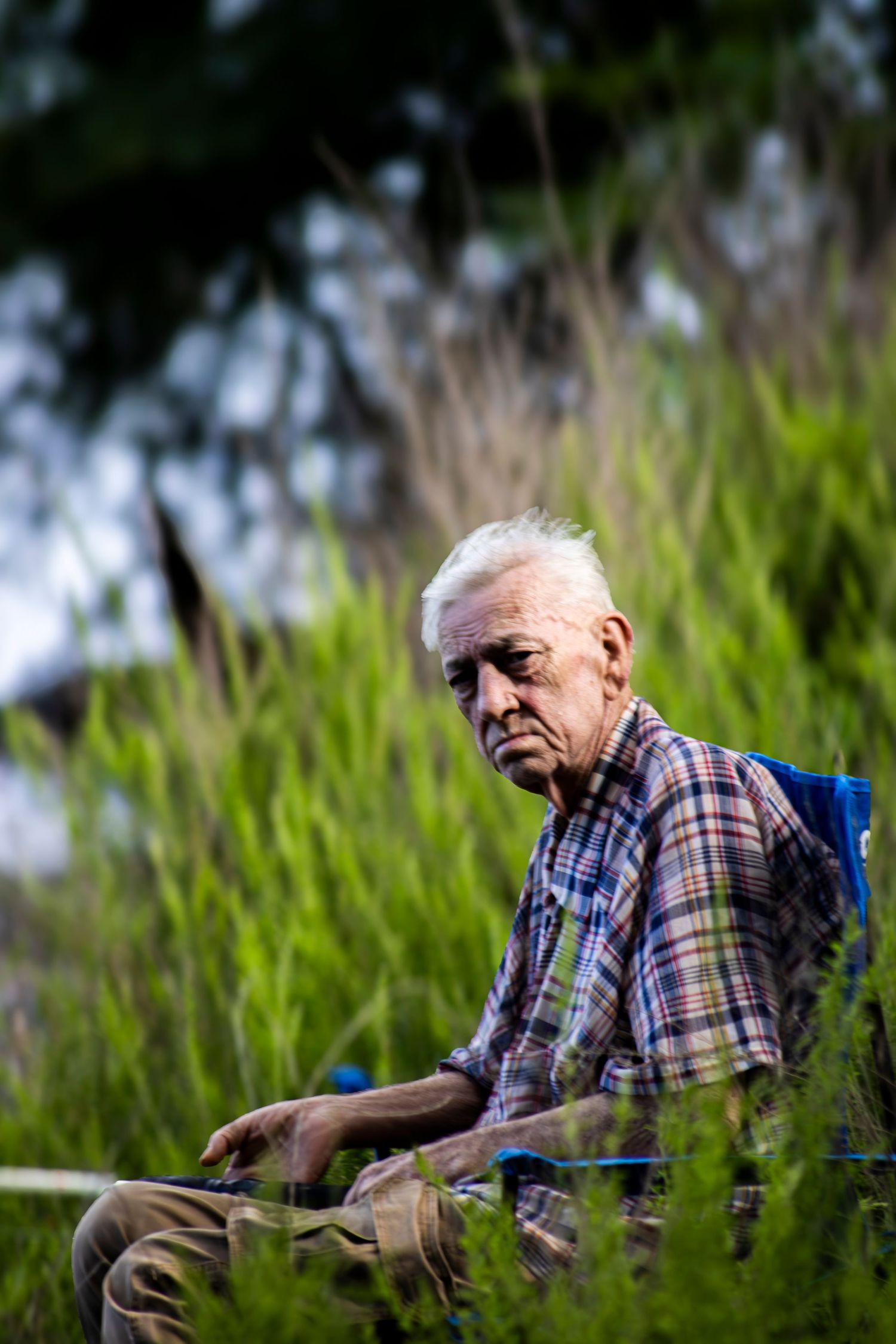 Cinematic film-style portrait of an older man sitting in a grassy field, photographed by Senbon Studio in Kentucky