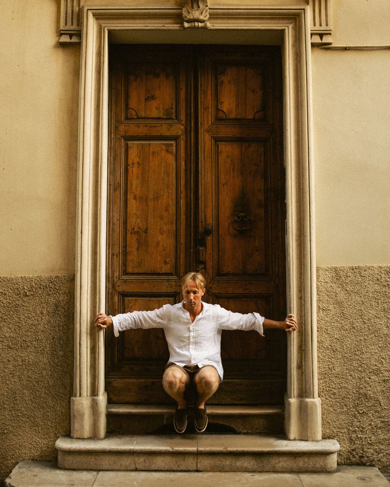 Logan Dance sitting in doorway of rustic wooden door on stone building steps in France.