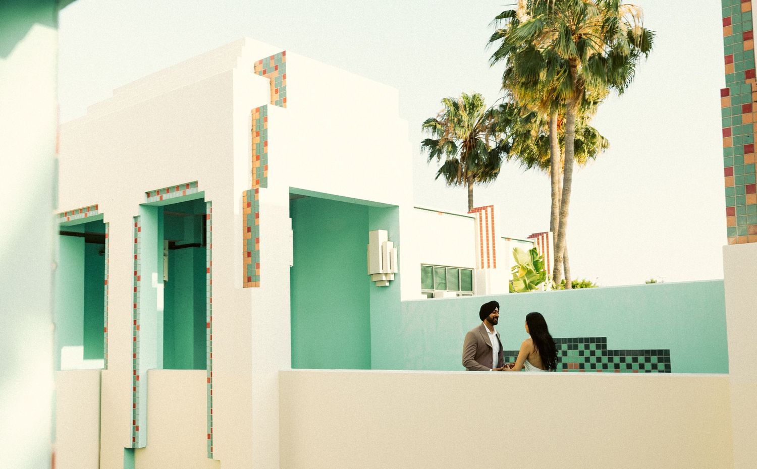 Couple sharing a quiet moment on a rooftop terrace with pastel mint walls and palm trees at the Beverly Hills City Hall.