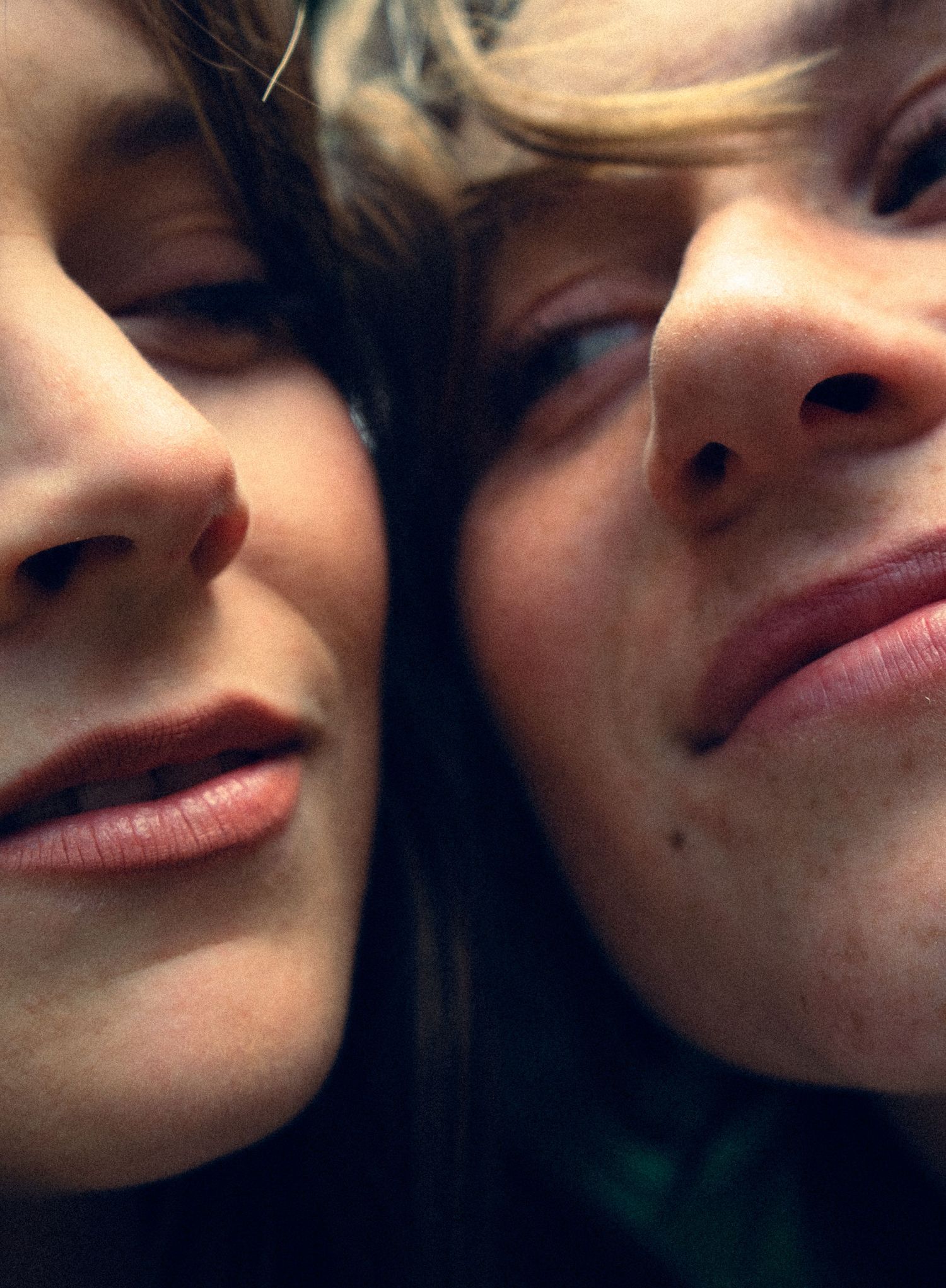 Extreme close-up of two people's faces pressed together, showing lips and noses in warm tones.