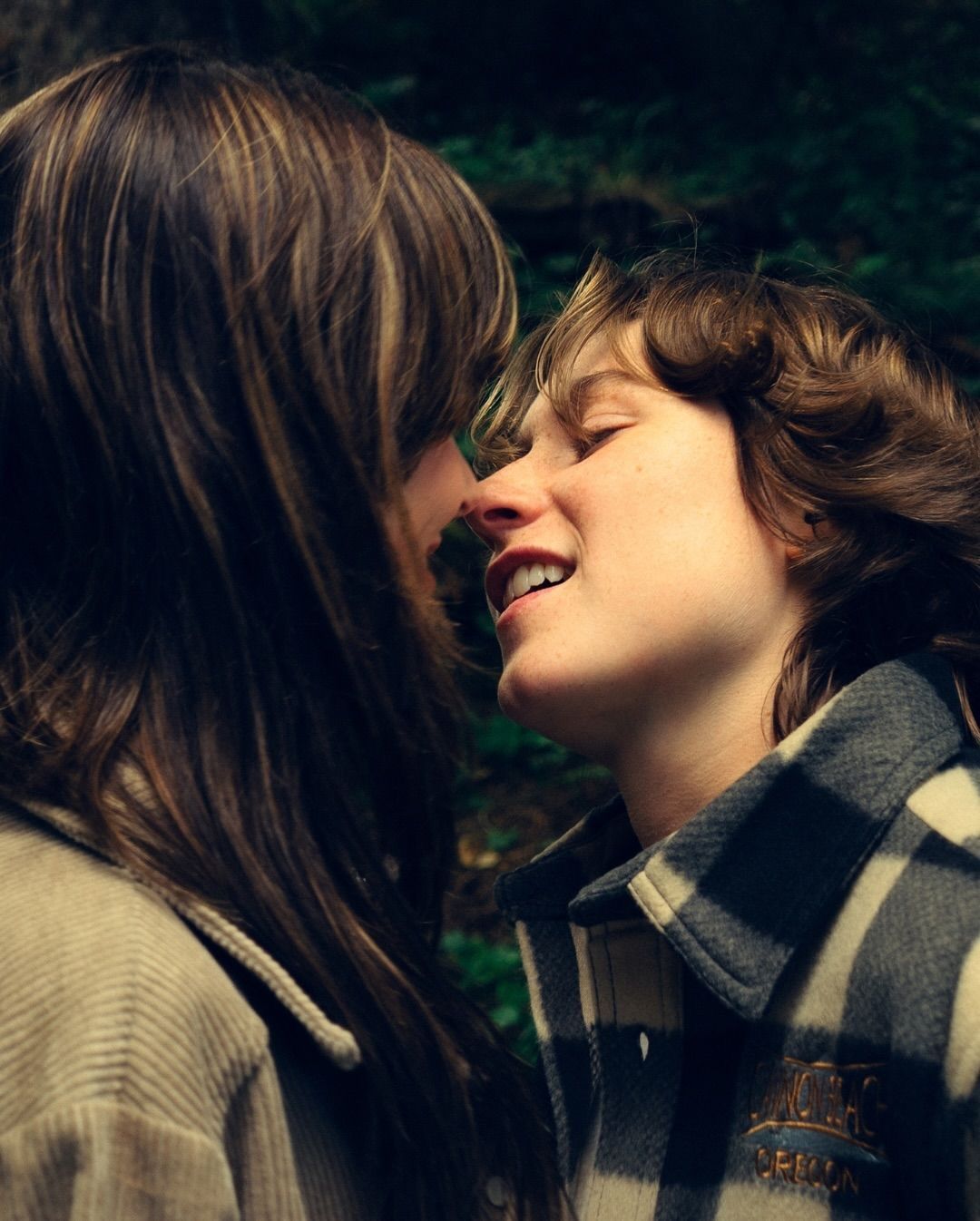 Two people sharing a joyful, intimate moment about to kiss outdoors in nature.
