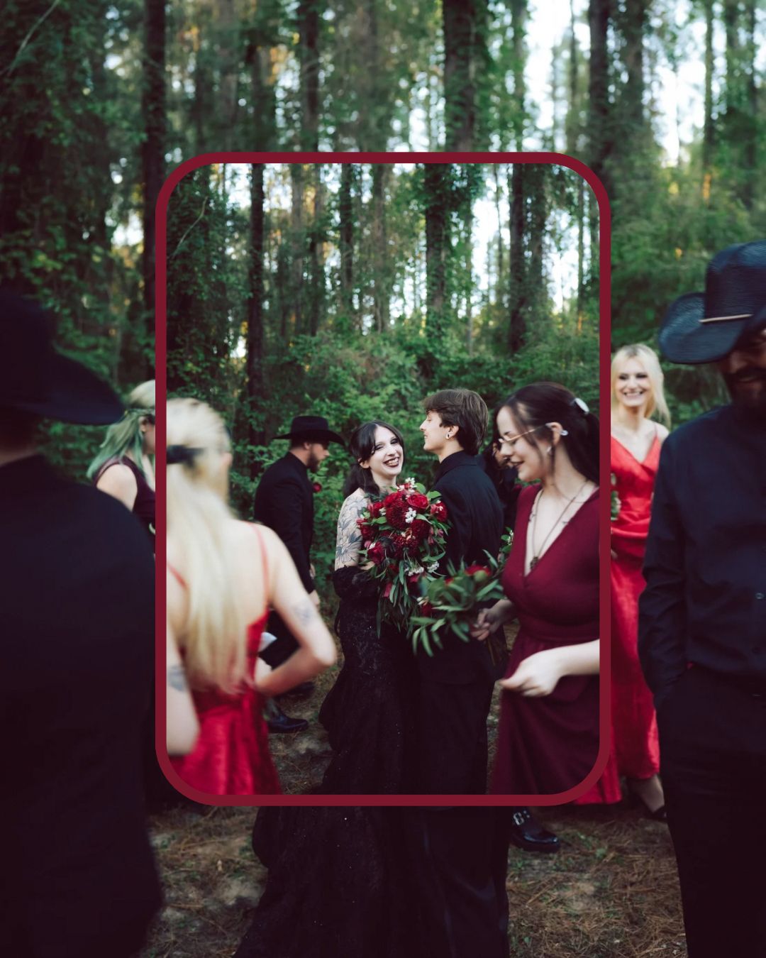Wedding party in black and red attire gathered in a forest, viewed through a red-framed mirror.