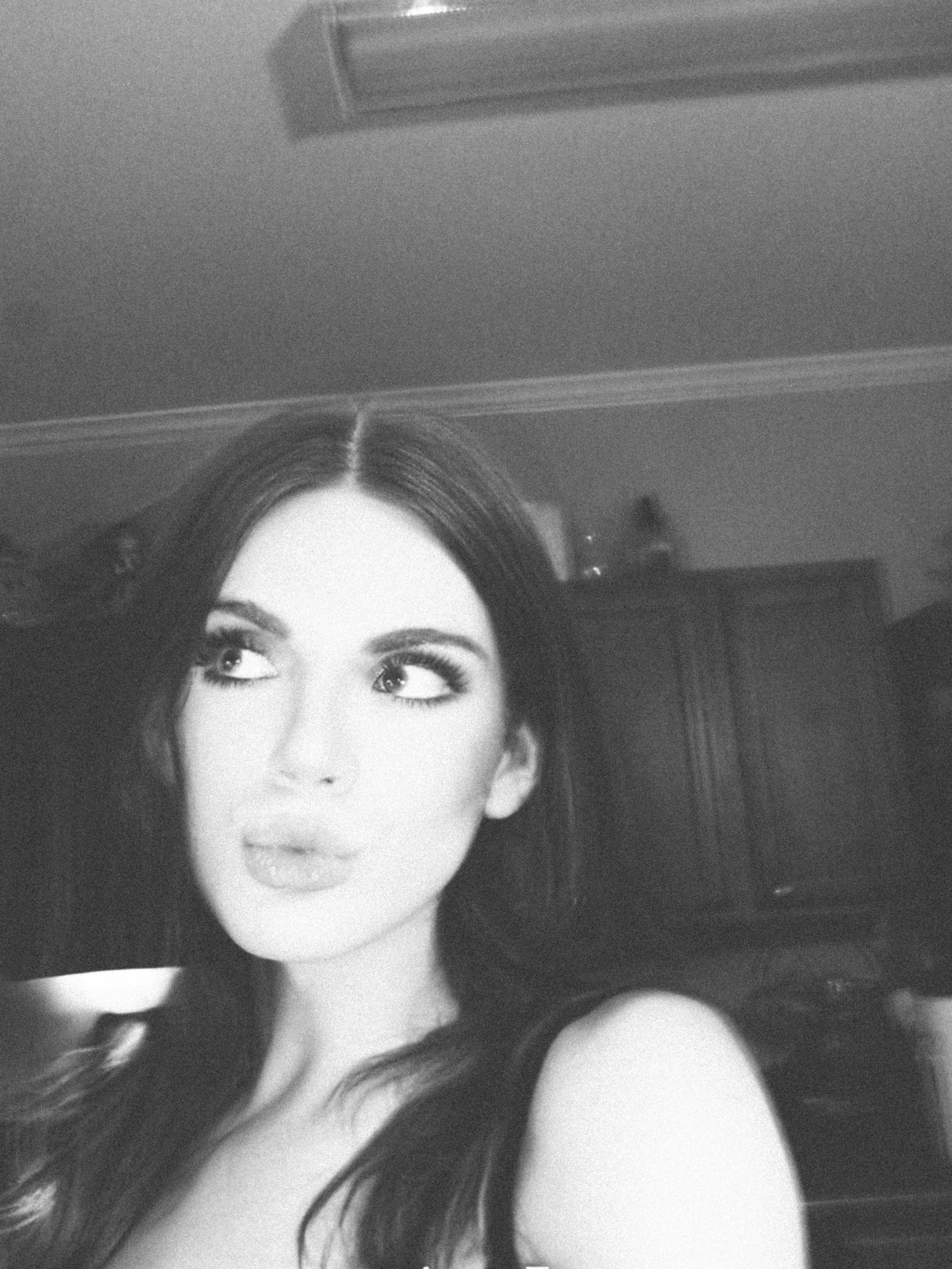 Black and white selfie of a young woman with dark hair and bold makeup making a pouty expression.