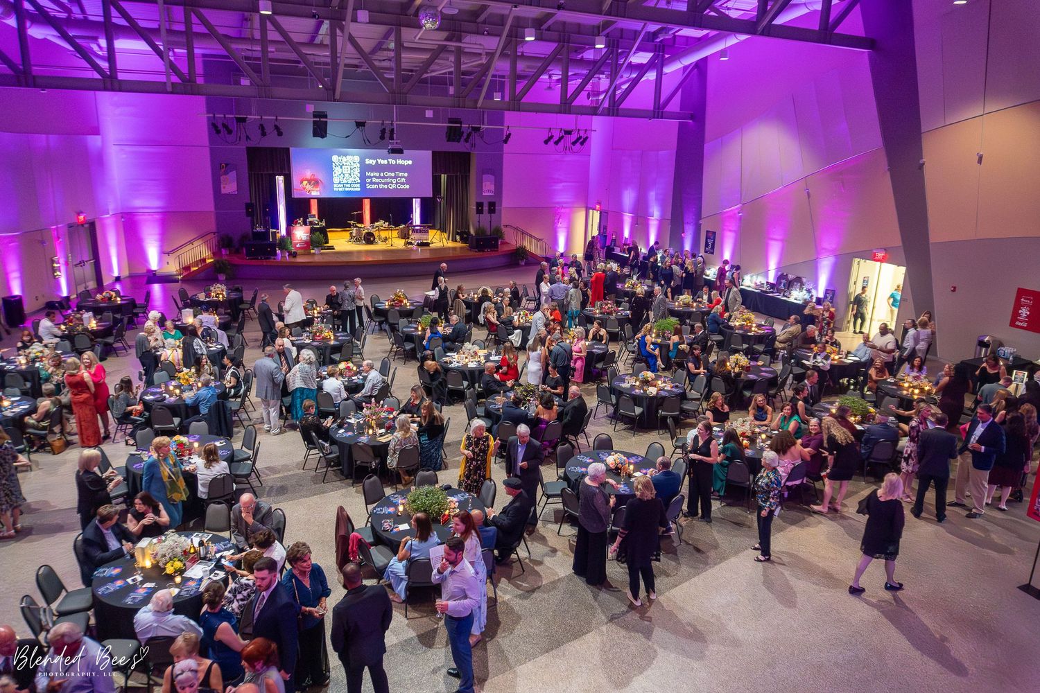 Overhead view of a large formal gala event with guests mingling and dining in a spacious venue.