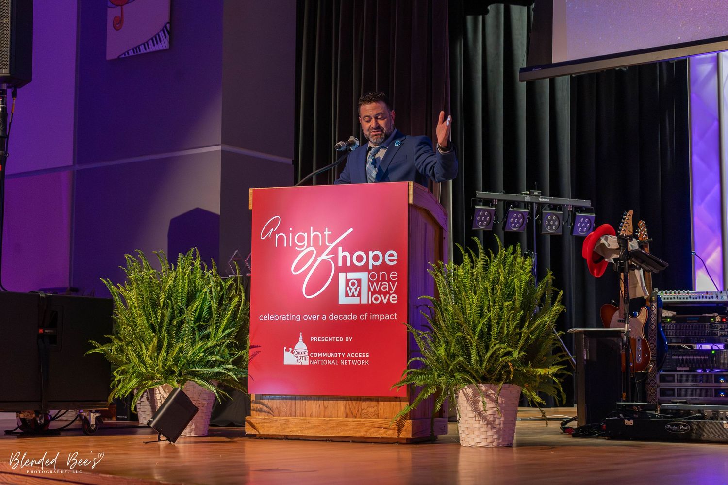 Speaker at a podium during a Night of Hope charity gala event with purple stage lighting.
