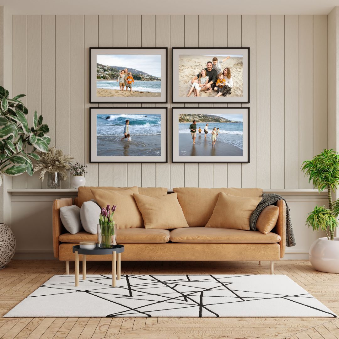 A cozy living room with a tan leather sofa, geometric rug, and four framed beach family photos arranged on a shiplap wall.