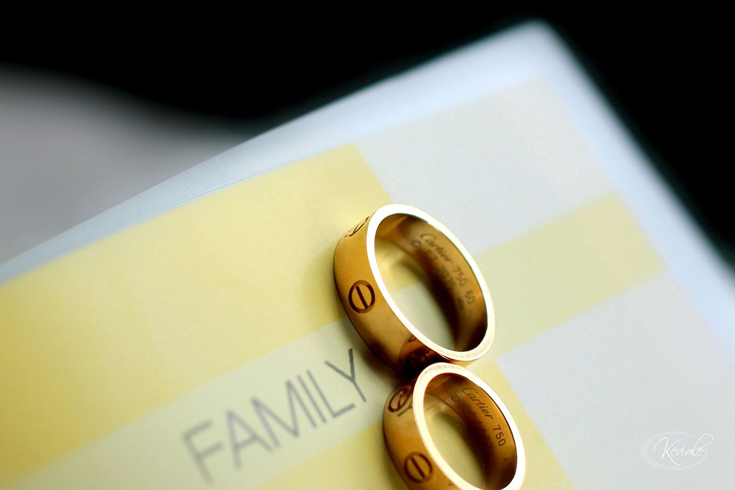 Two gold Cartier wedding bands placed on a paper with the word Family printed on it.