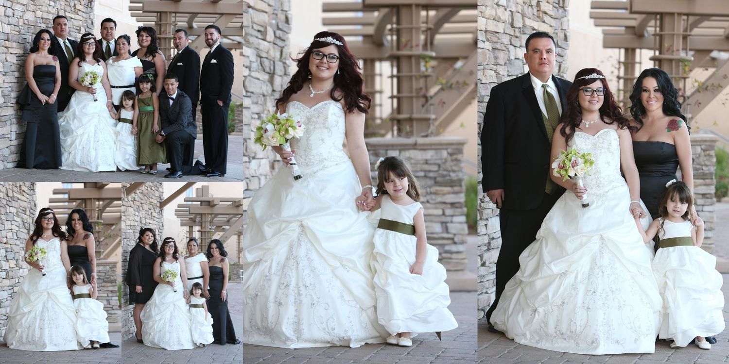 Wedding party poses in white gowns and black suits outside a stone venue, featuring bride, groom, bridesmaids, and flower girl.