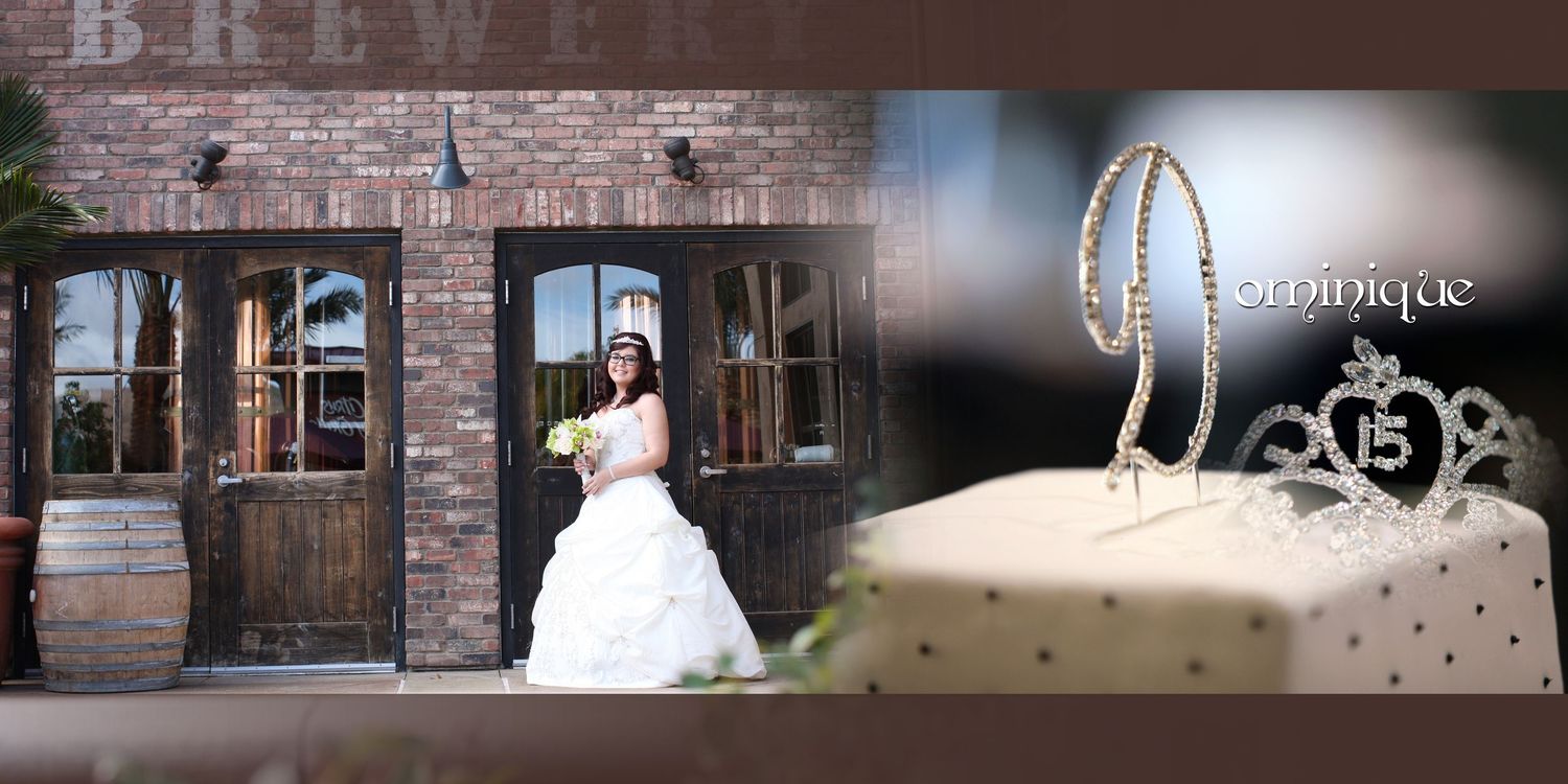 A quinceañera girl in a white ball gown poses outside a brick building beside a decorated cake and diamond tiara jewelry.