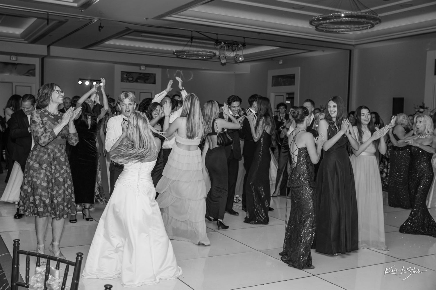 Black and white photo of wedding guests dancing joyfully on the dance floor during a elegant wedding reception.