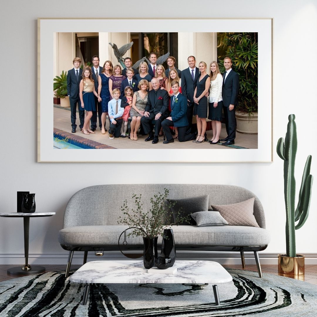 Framed large family portrait photo displayed above a modern gray sofa in an elegant living room with cactus decor.